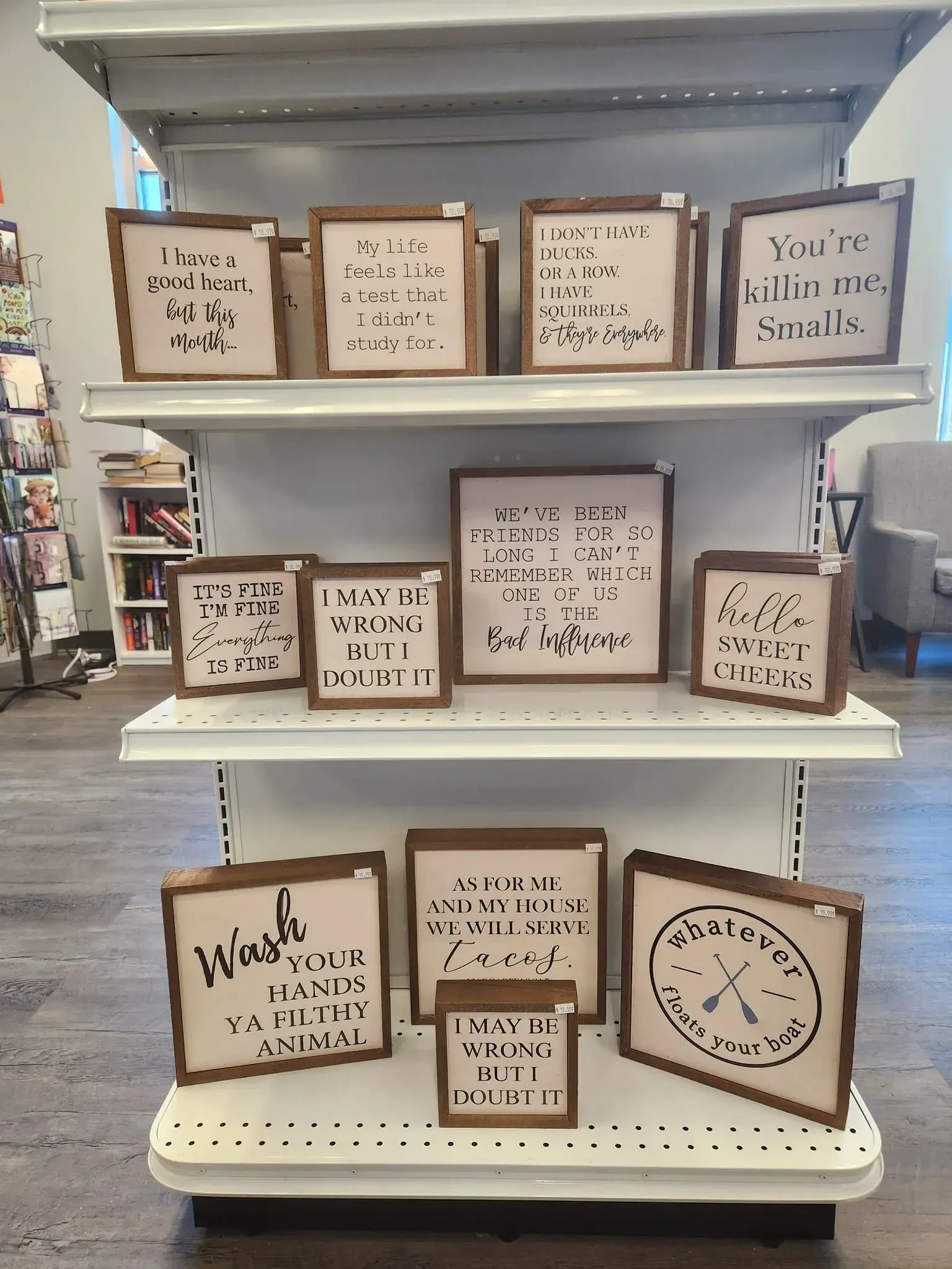 Shelves with wooden framed signs featuring various quotes in a store.