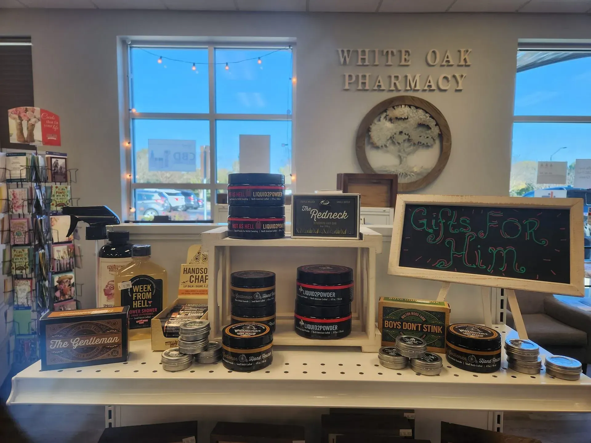 White Oak Pharmacy storefront with gift display: candles, lotions, and handwritten signs.