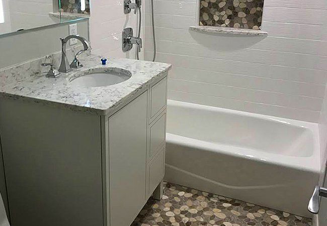 A bathroom with a sink , tub and mirror.