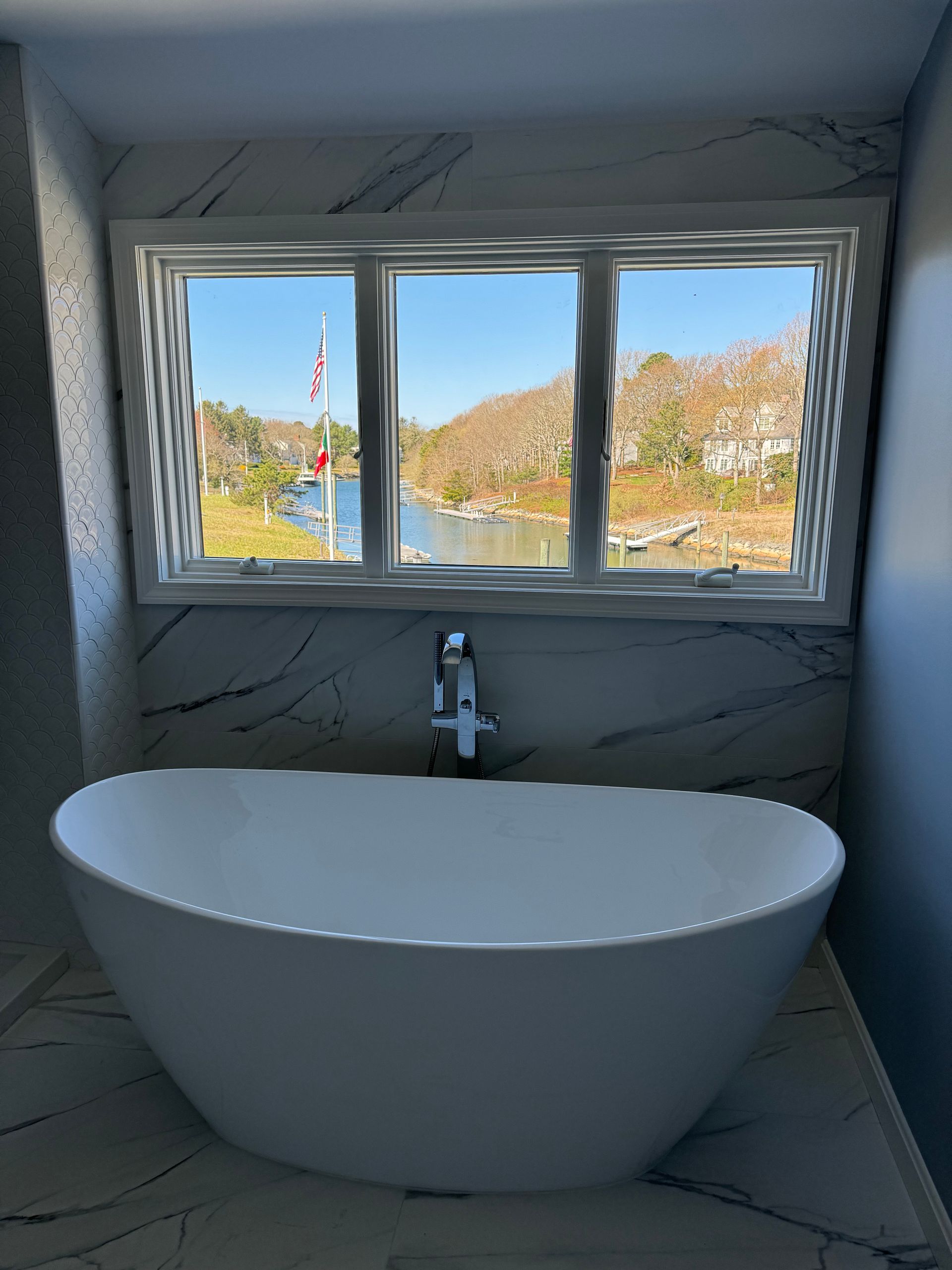 A bathroom with a tub and a window with a view of a body of water