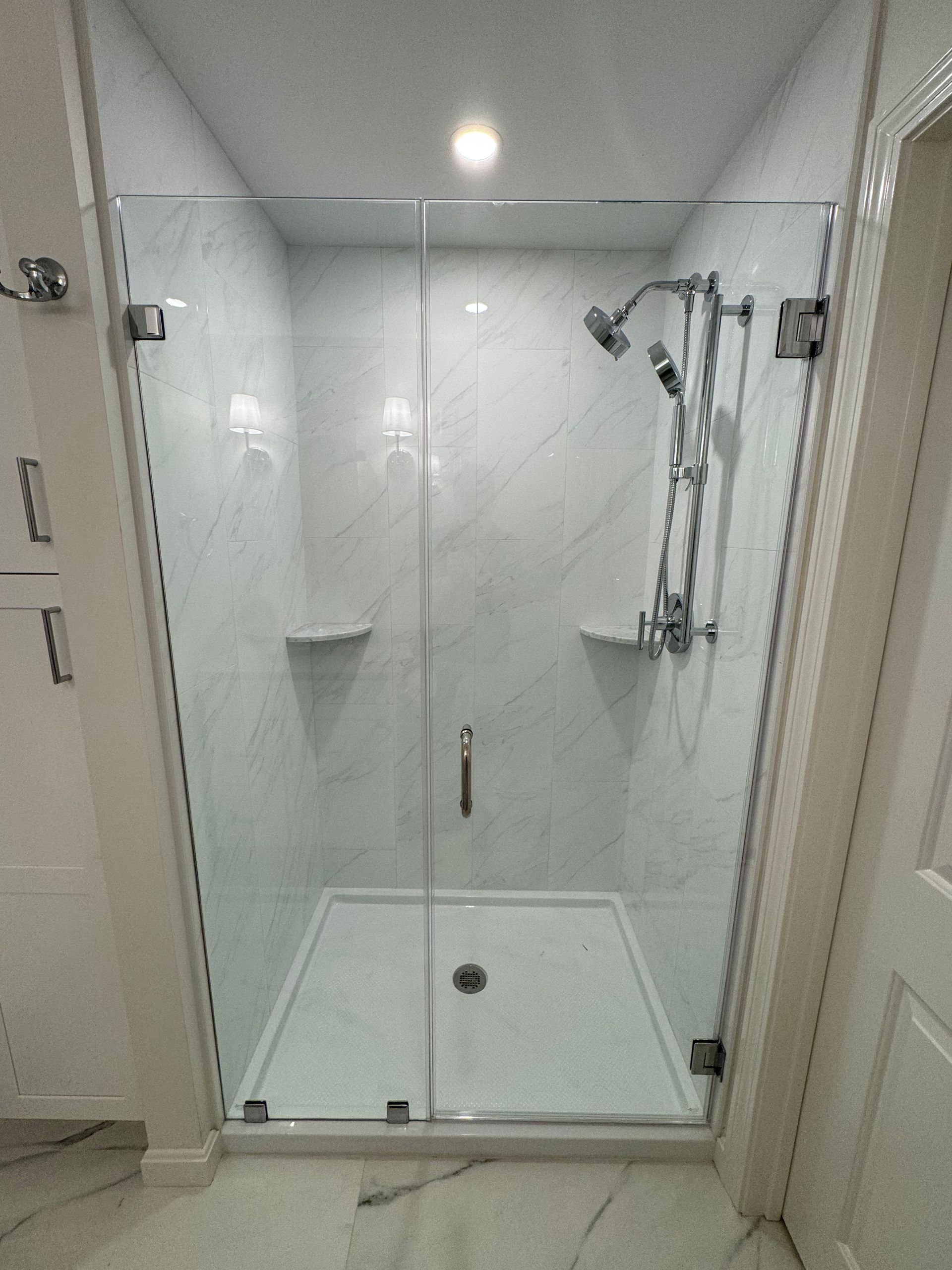 A bathroom with a walk in shower with a glass door.