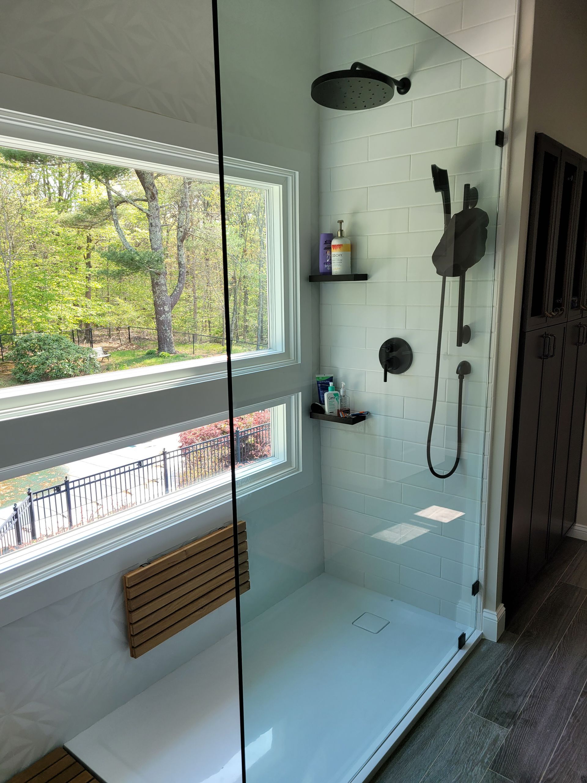A bathroom with a walk in shower and a window.