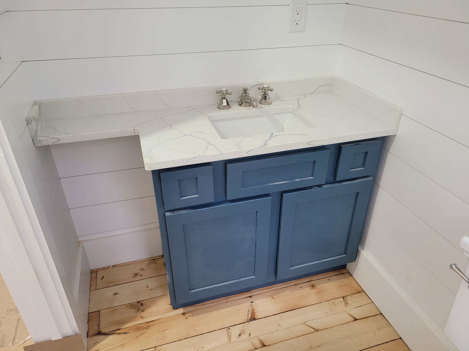 A bathroom vanity with blue cabinets and a white counter top.
