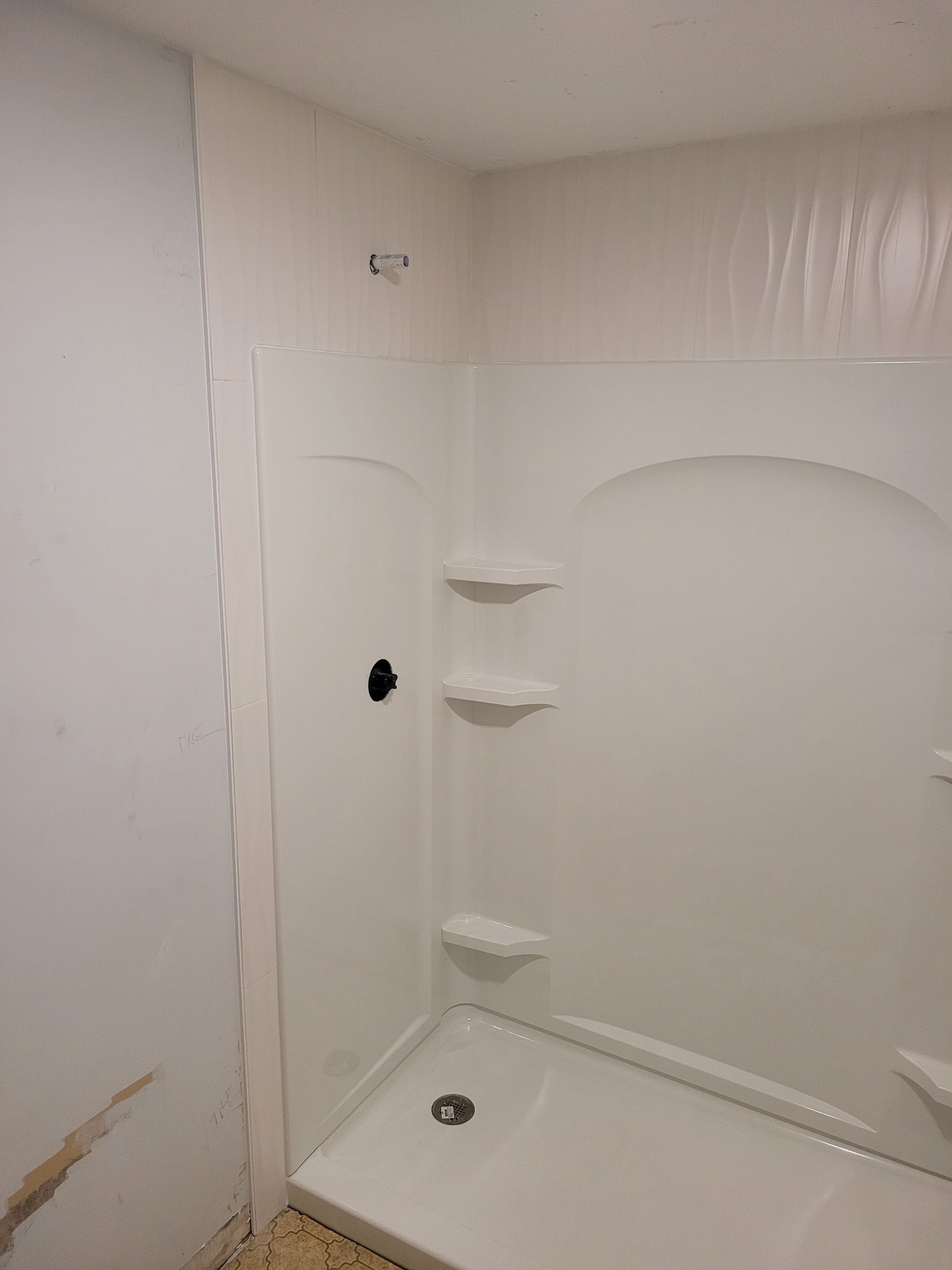 A bathroom with a shower stall and shelves.