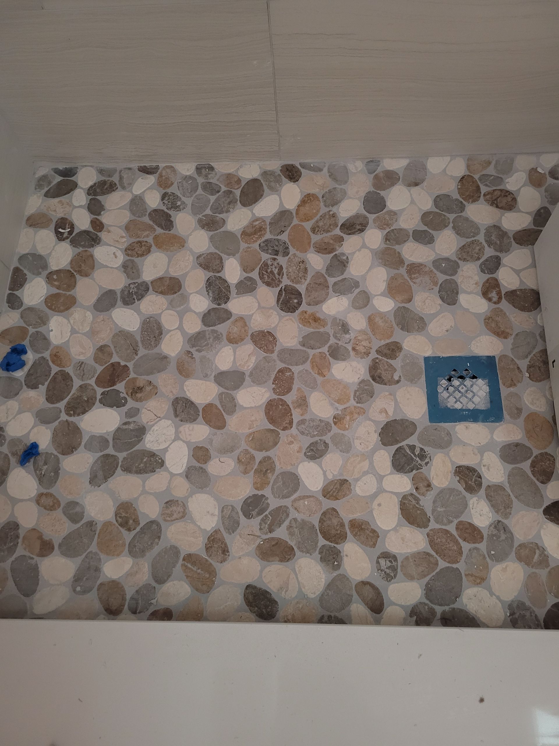 A shower stall with a tile floor made of rocks.