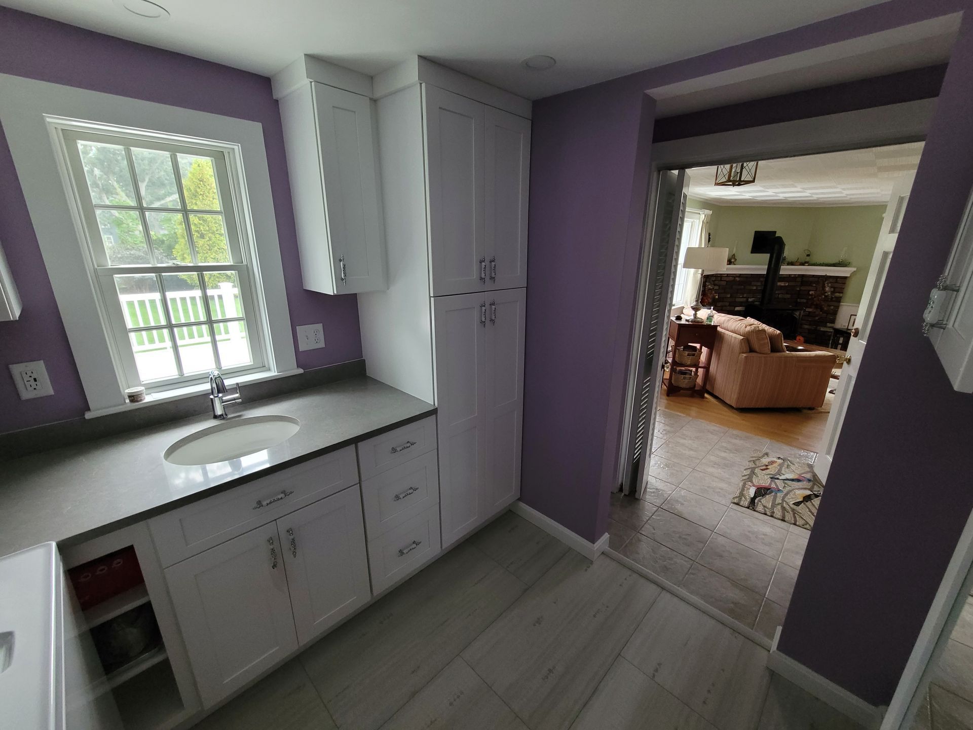 A kitchen with purple walls and white cabinets and a sink