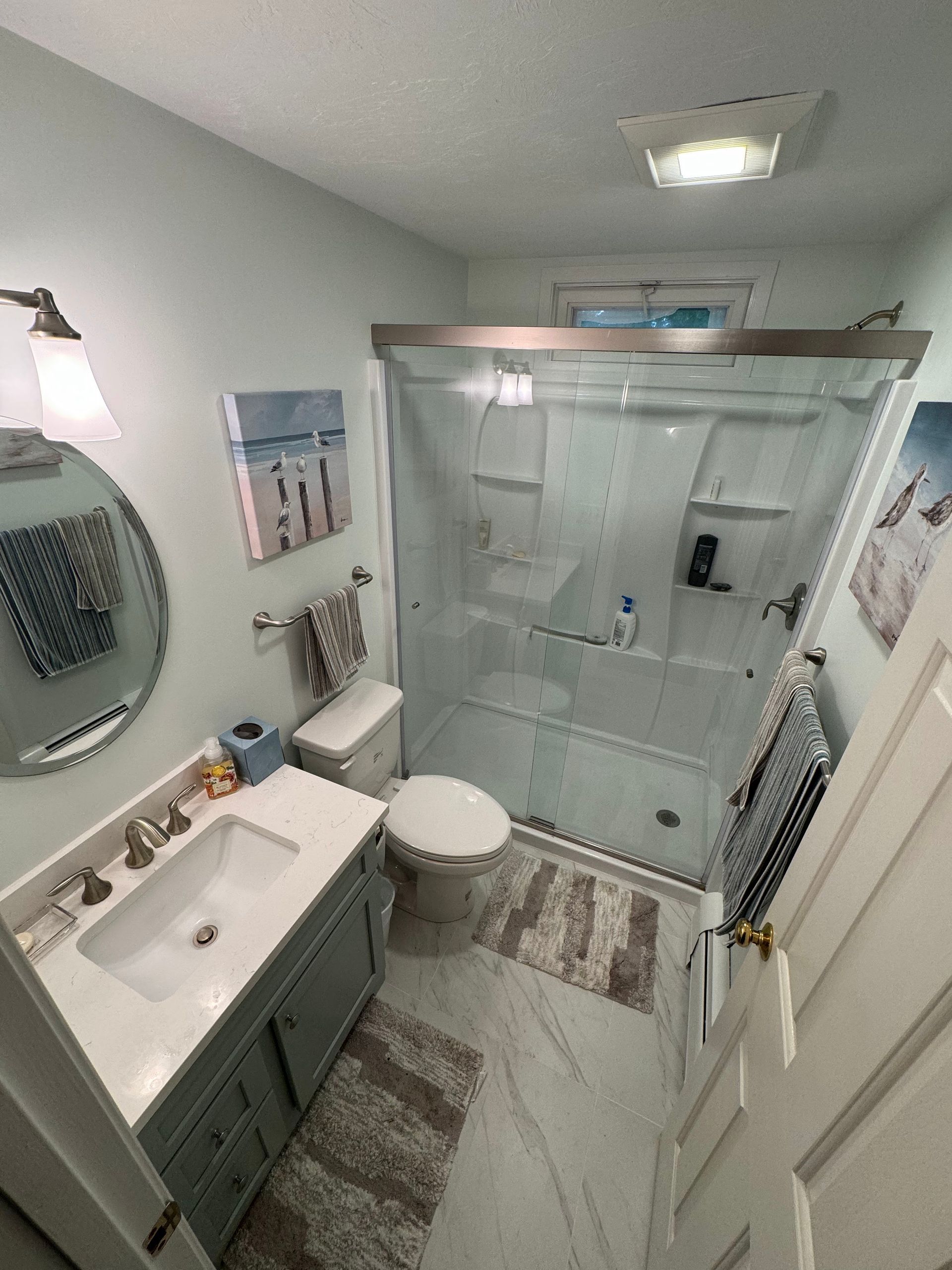 A bathroom with a sink , toilet , shower and mirror.