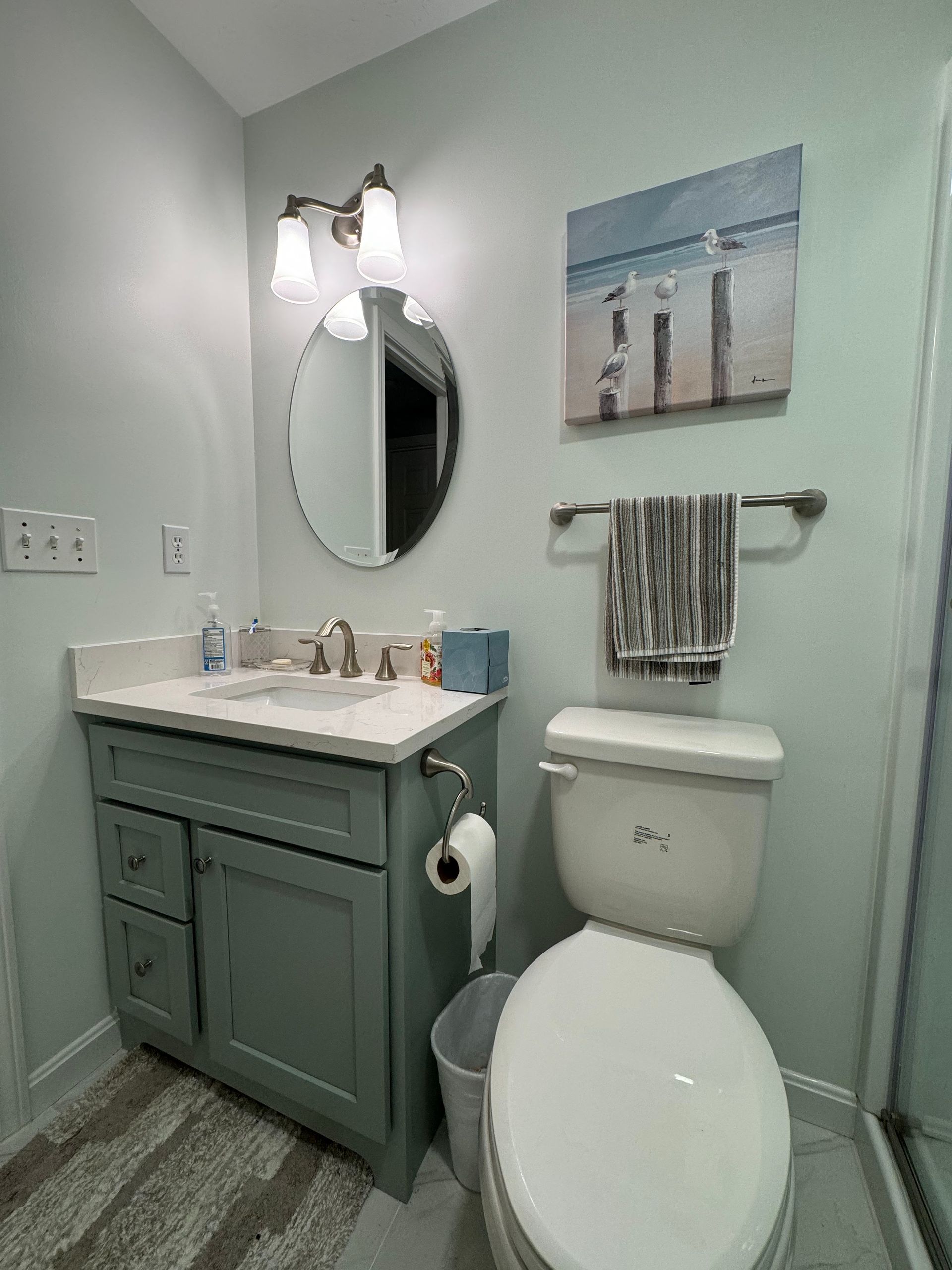 A bathroom with a toilet , sink , mirror and shower.