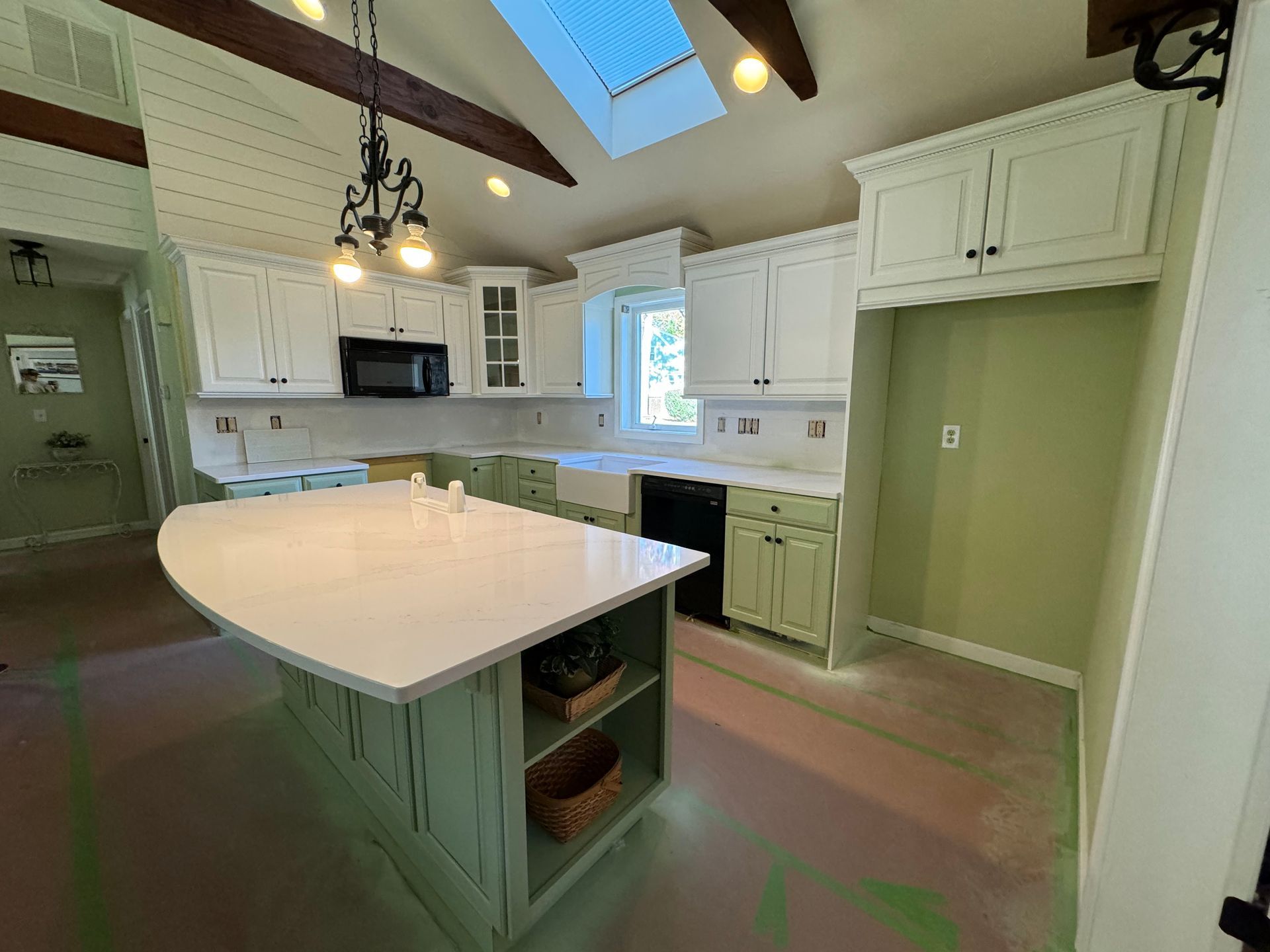 A kitchen with white cabinets and a large island in the middle.