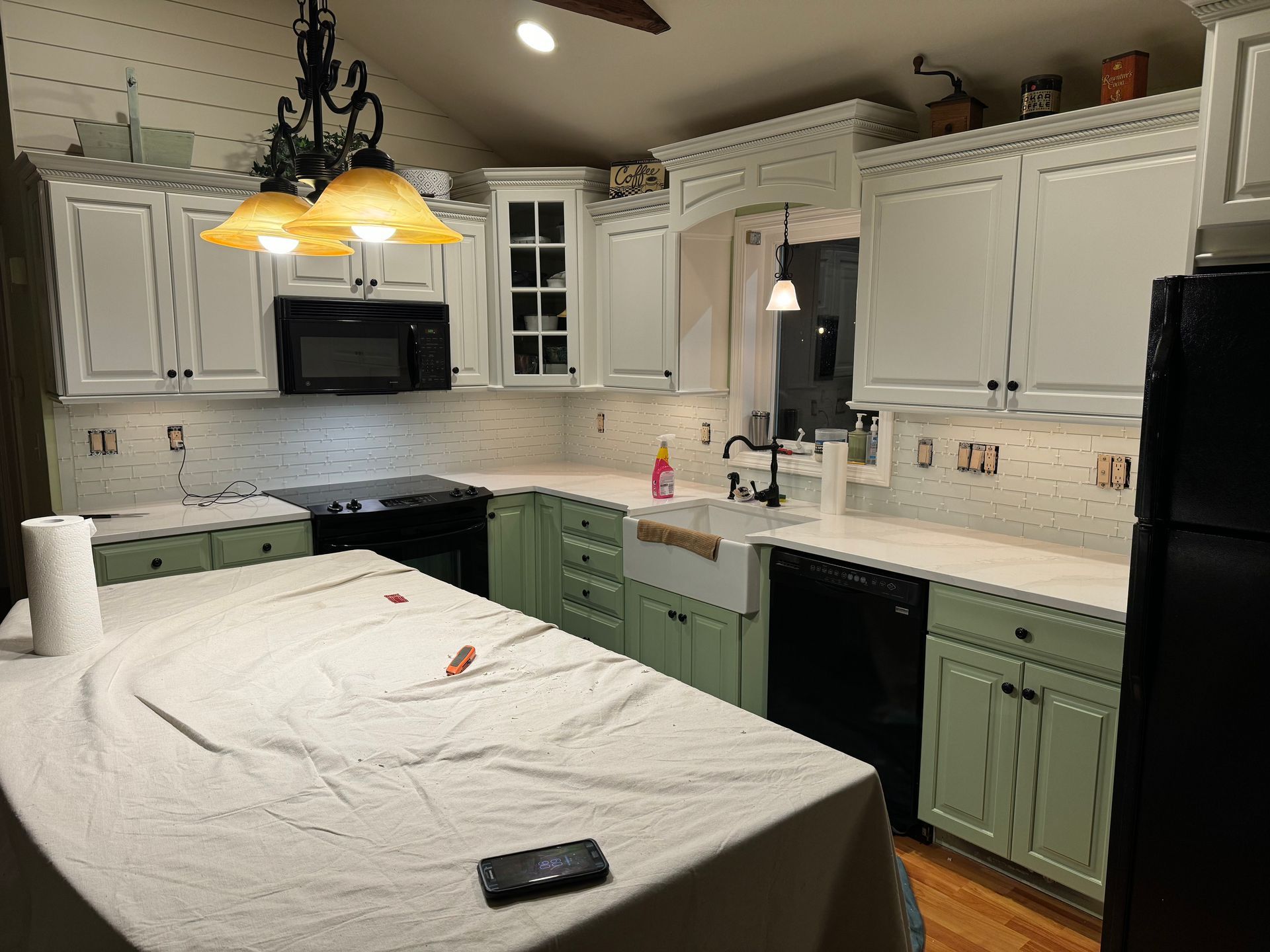 A kitchen with green cabinets and white counter tops.