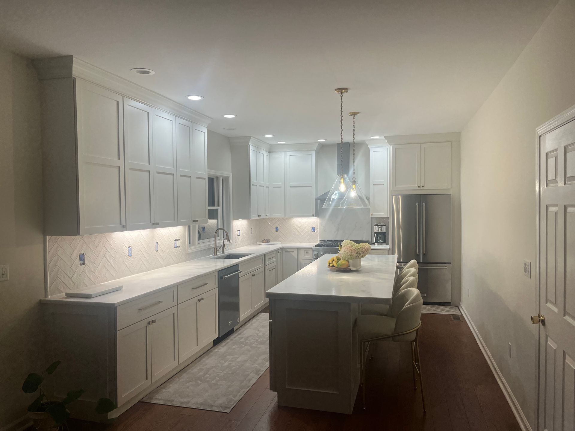 A kitchen with white cabinets , stainless steel appliances , and a large island.