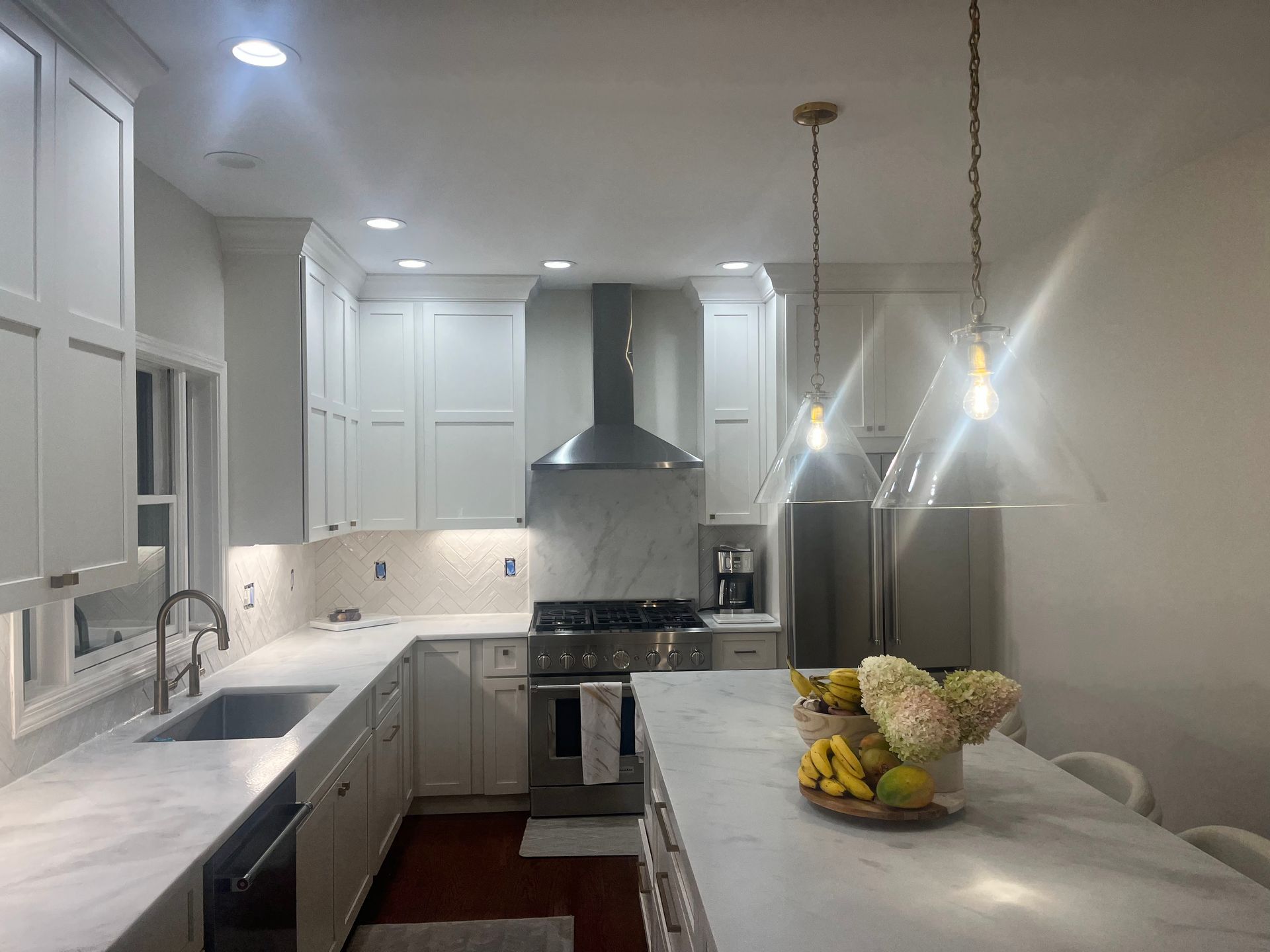 A kitchen with white cabinets , stainless steel appliances , a sink , and a large island.