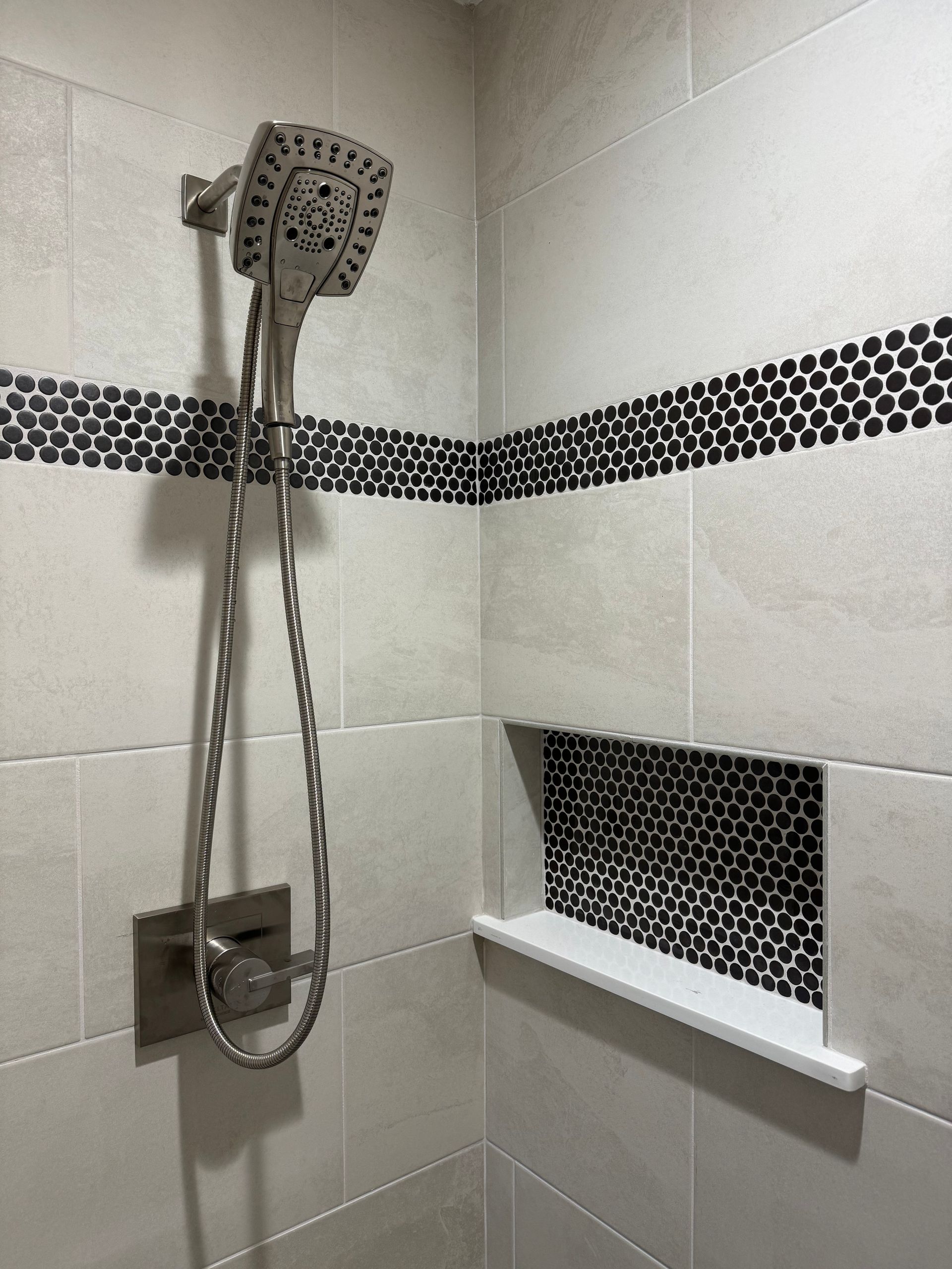 A shower head is hanging from the wall in a bathroom.