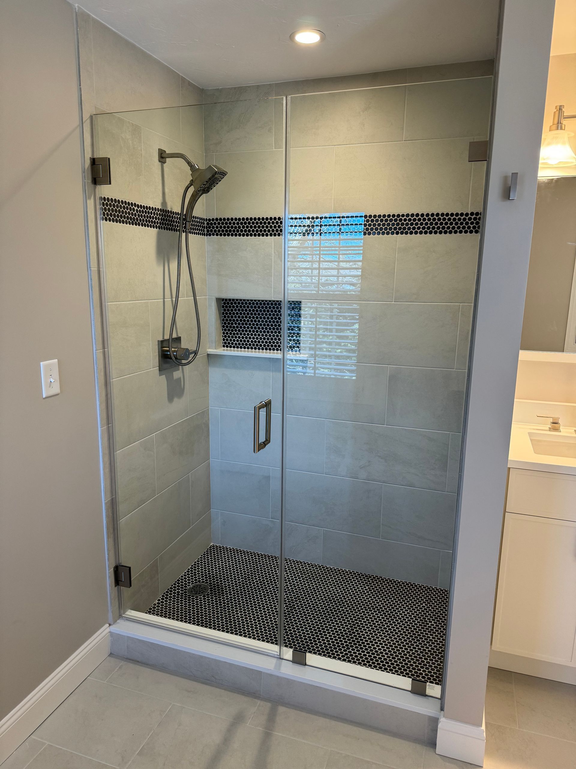 A bathroom with a walk in shower with a glass door.