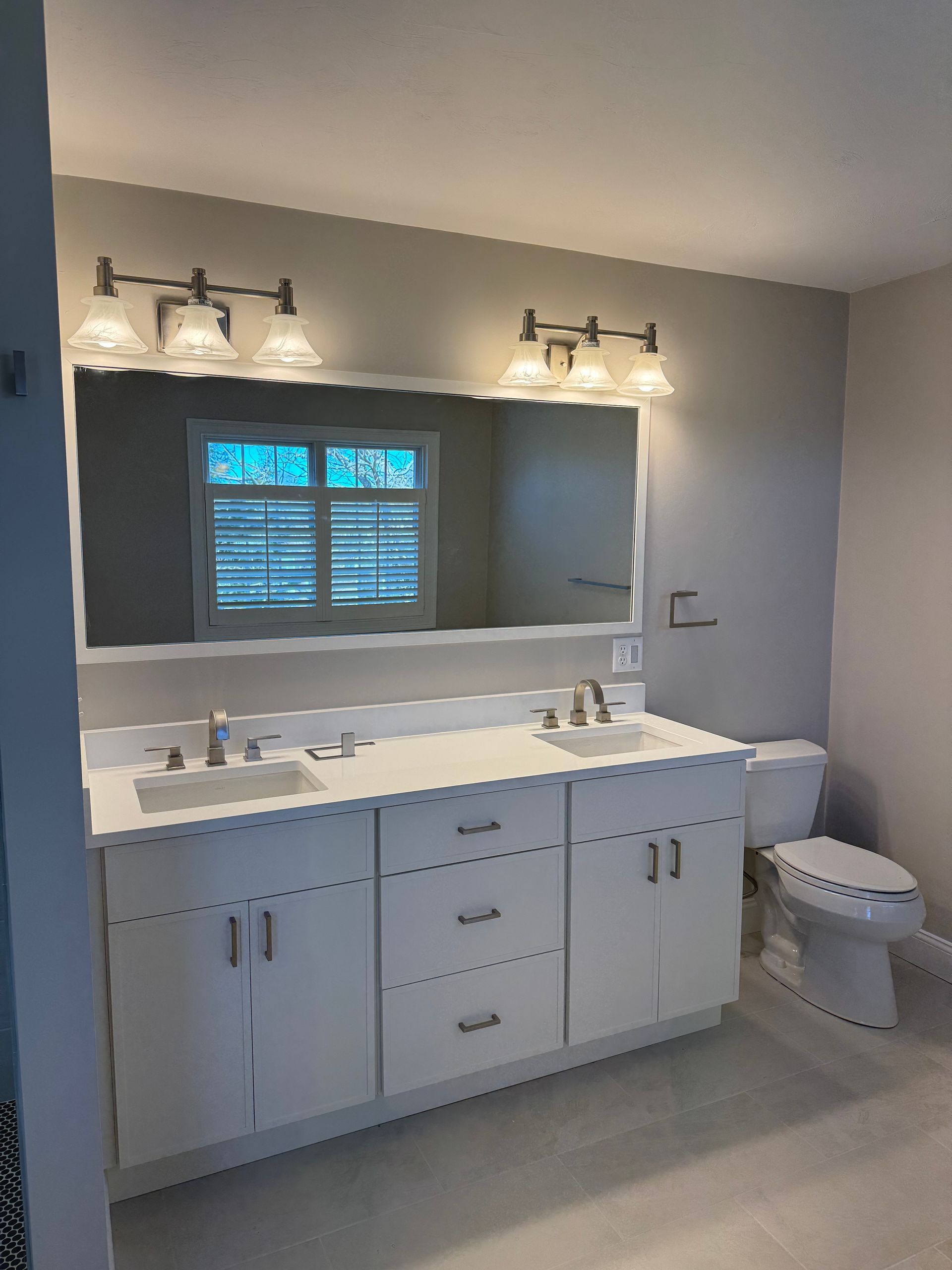A bathroom with two sinks , a toilet , and a large mirror.