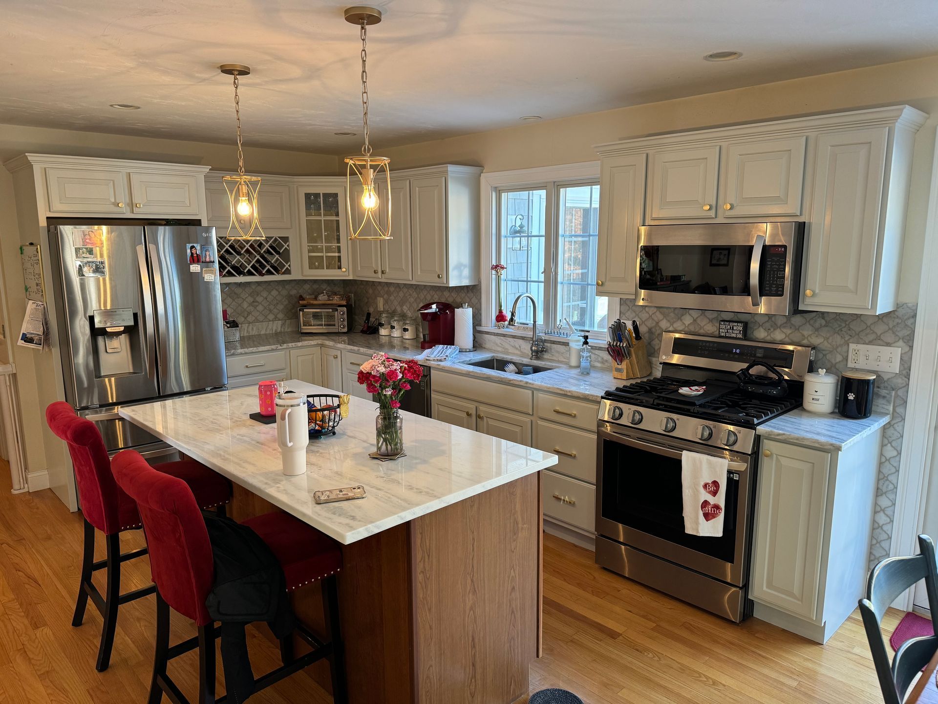 A kitchen with white cabinets , stainless steel appliances , and a large island.