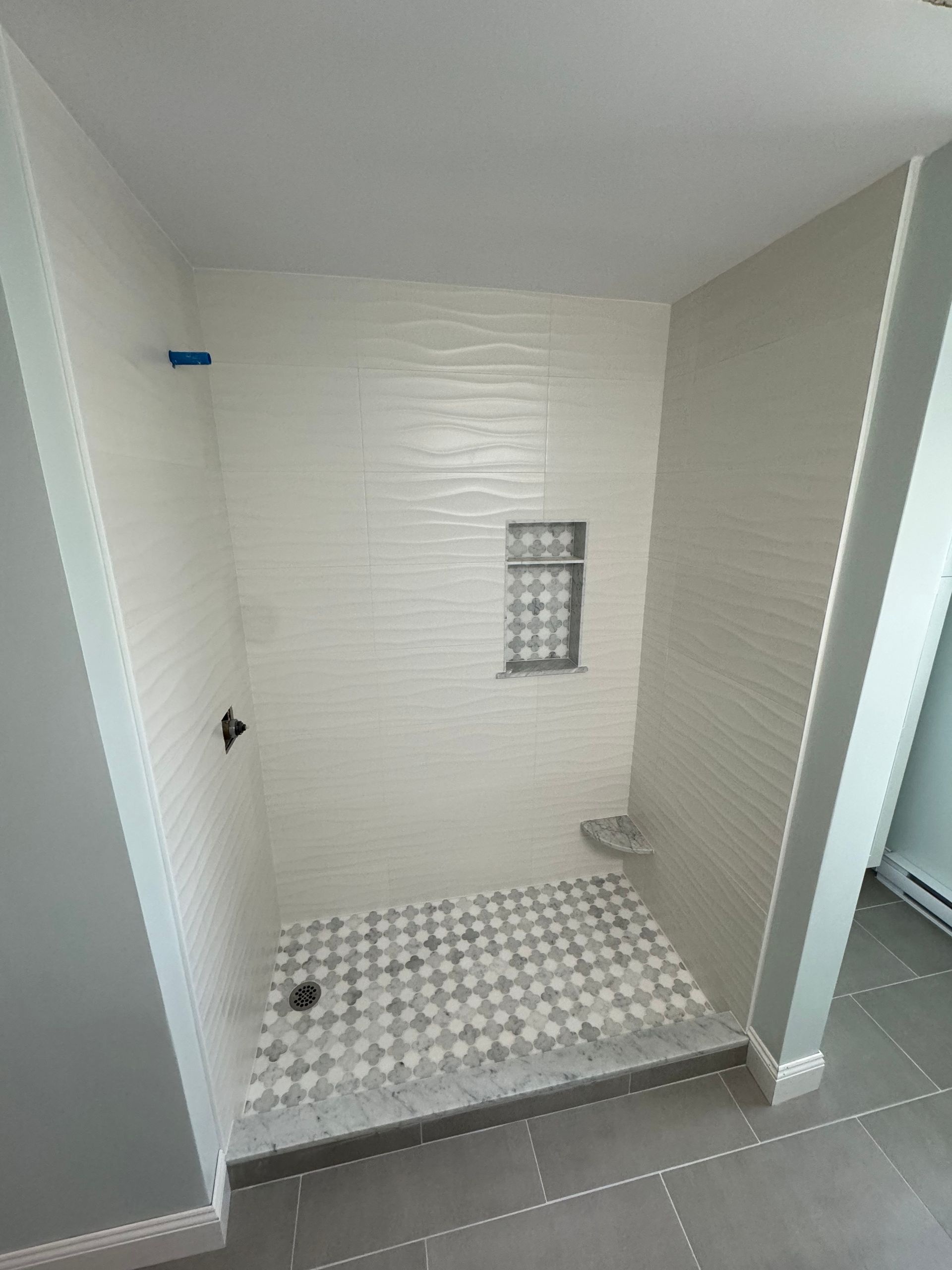 A bathroom with a walk in shower and a tiled floor.