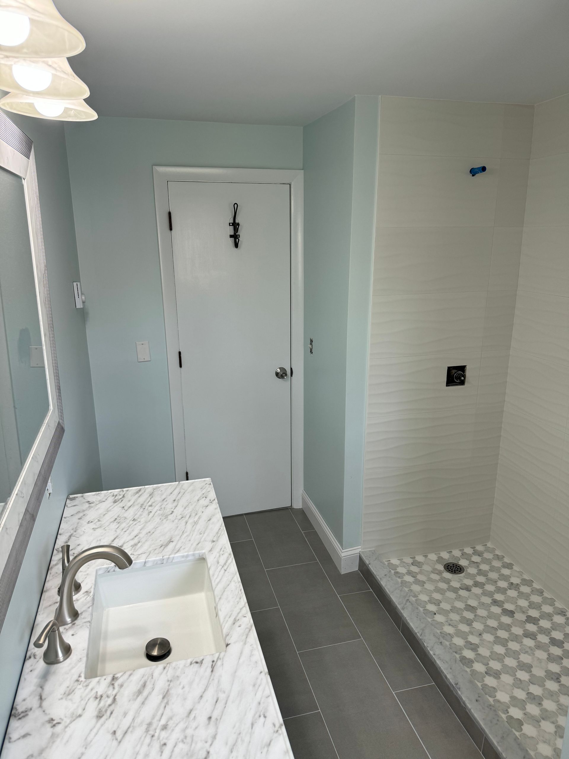 A bathroom with a sink , mirror and shower.