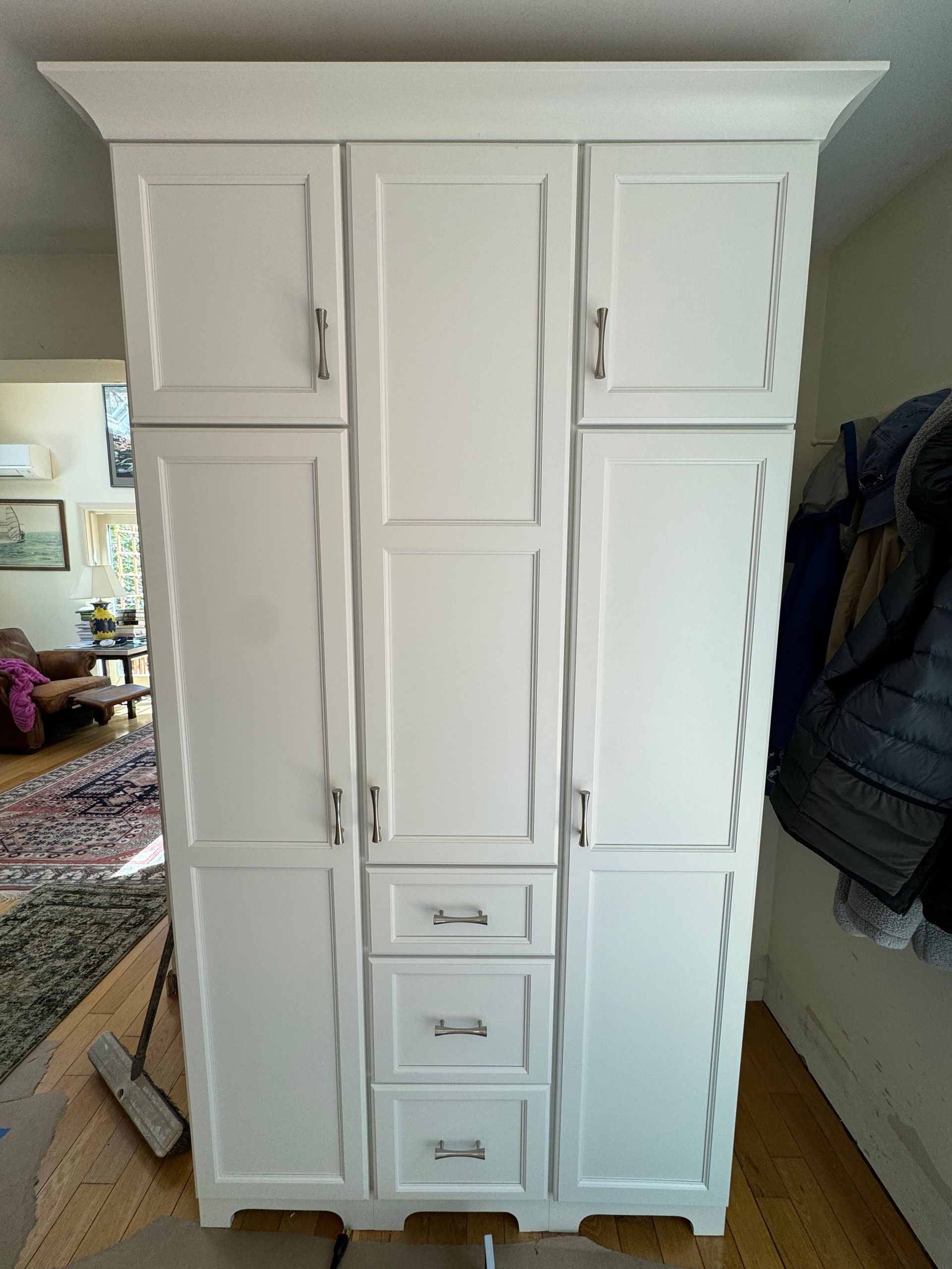 A large white cabinet with drawers and doors is sitting in a living room.