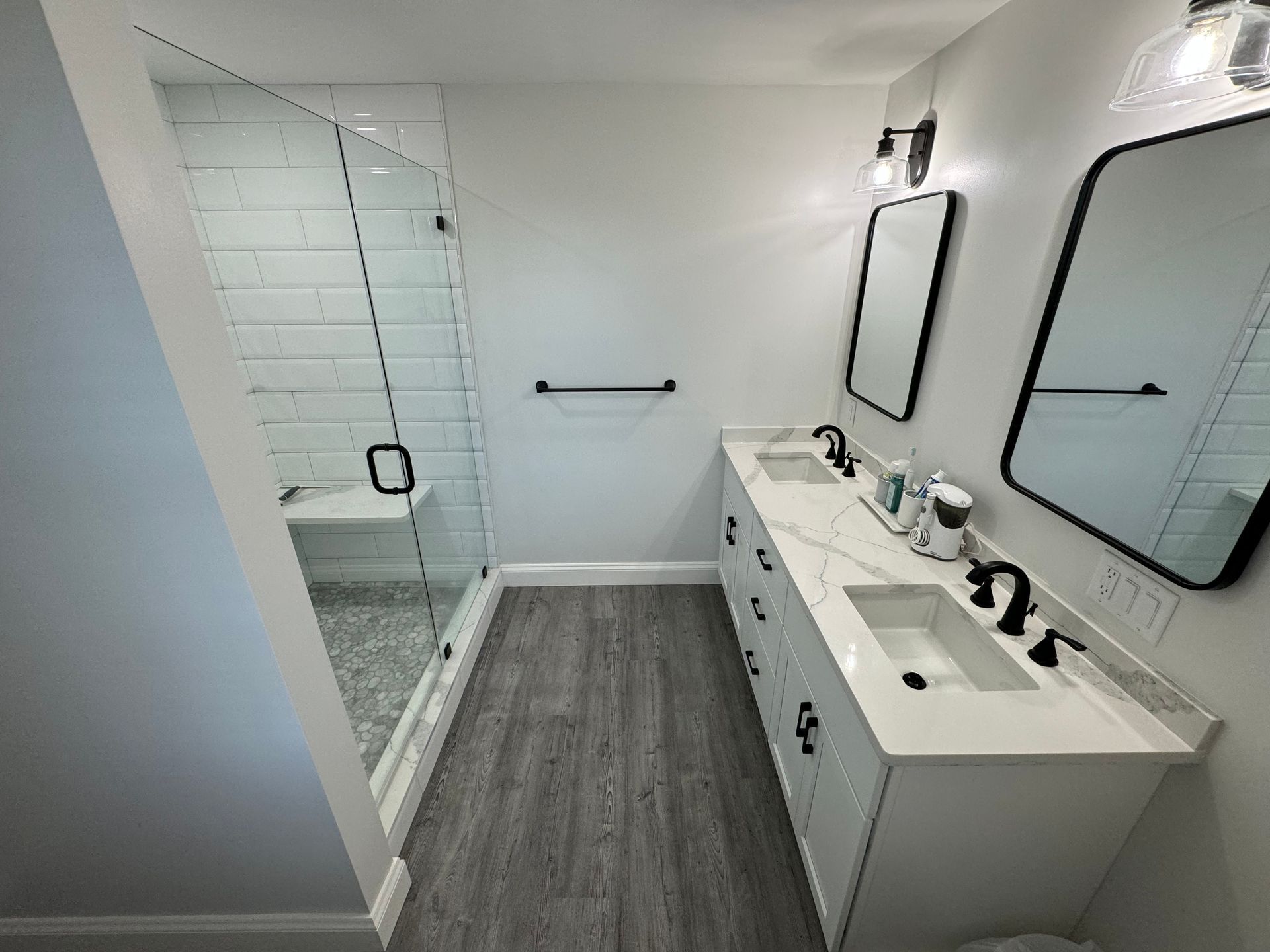 A bathroom with two sinks and a walk in shower.