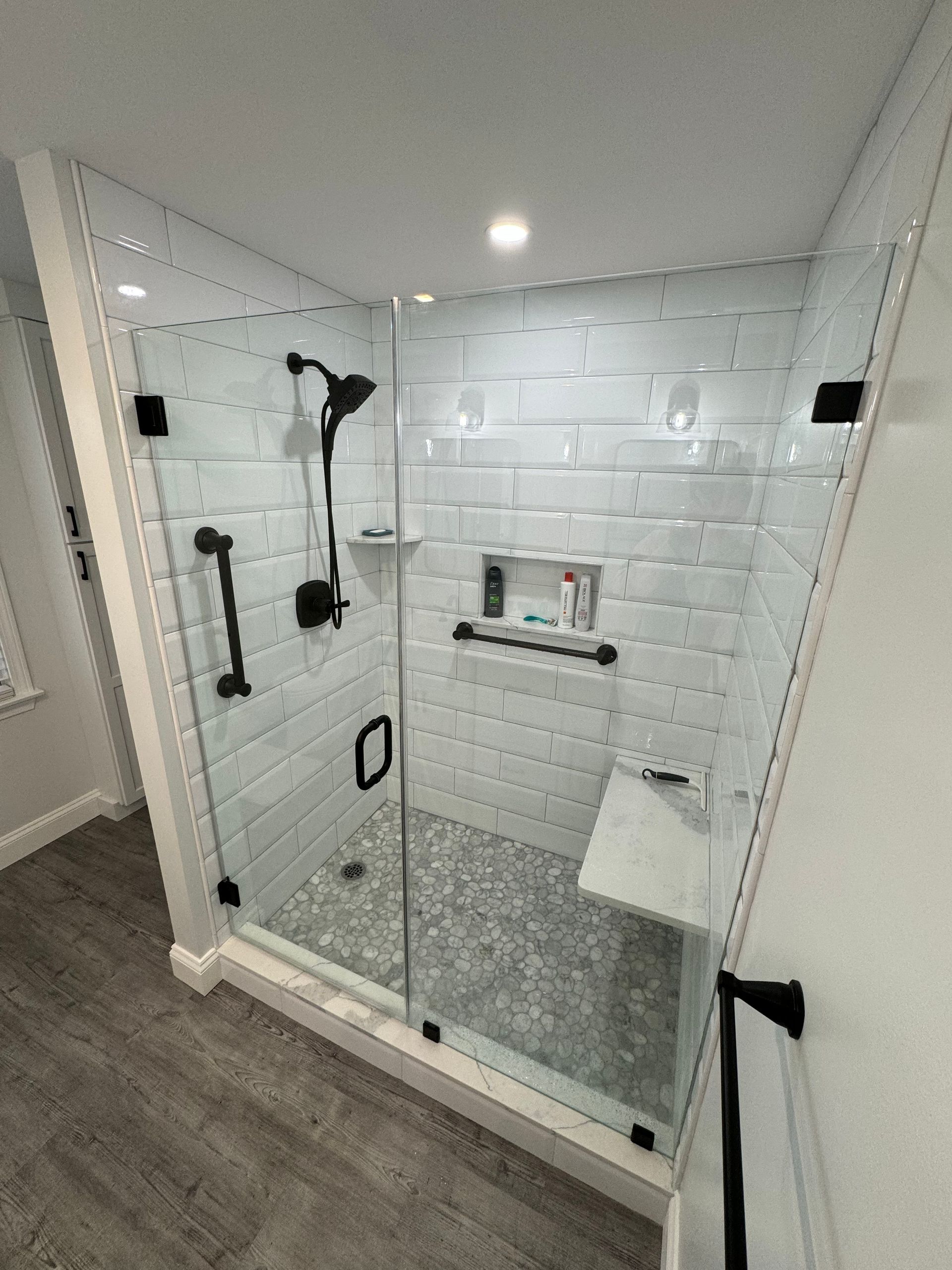 A bathroom with a walk in shower with a glass door.