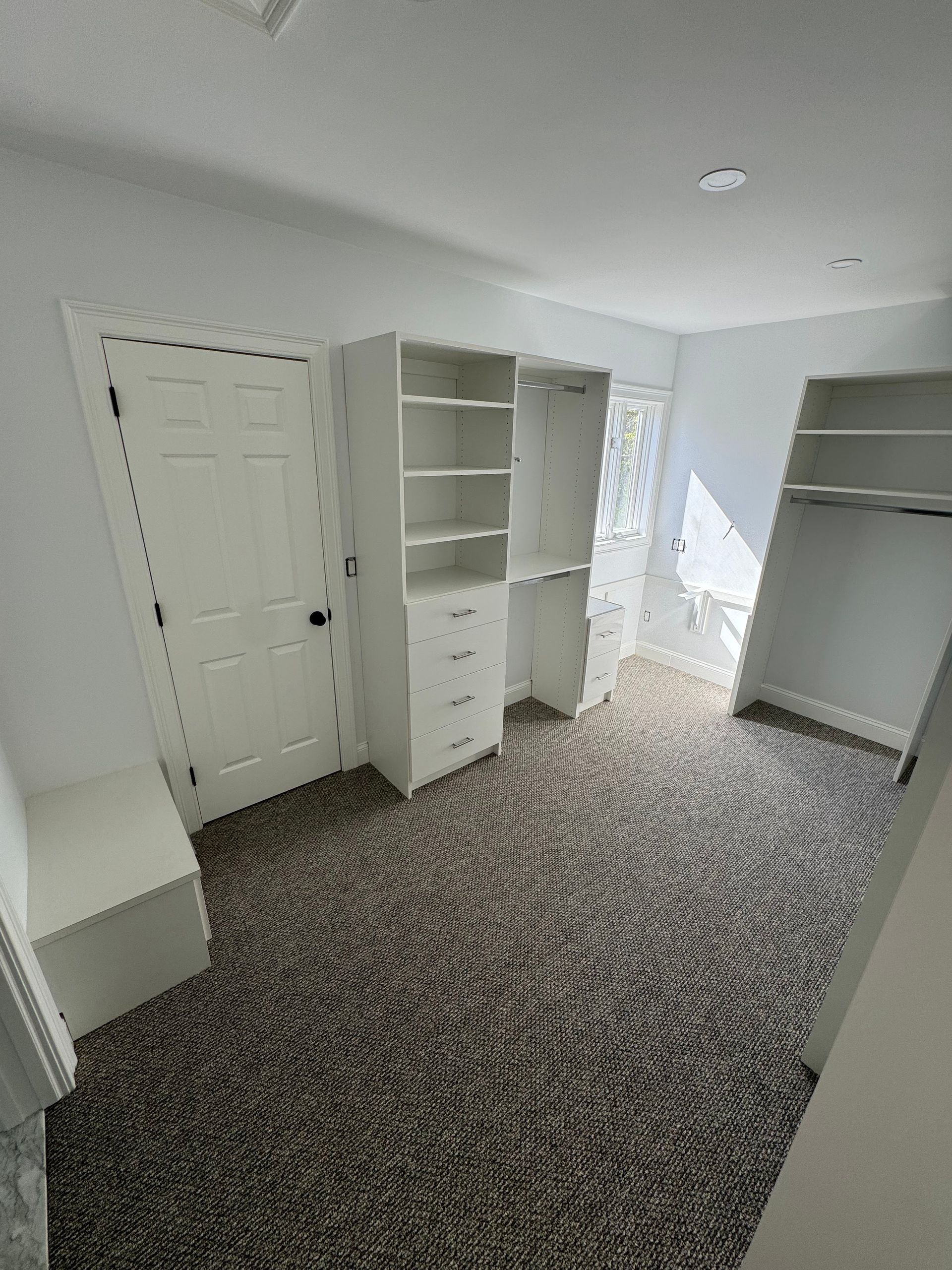 A bedroom with a walk in closet and a carpeted floor.