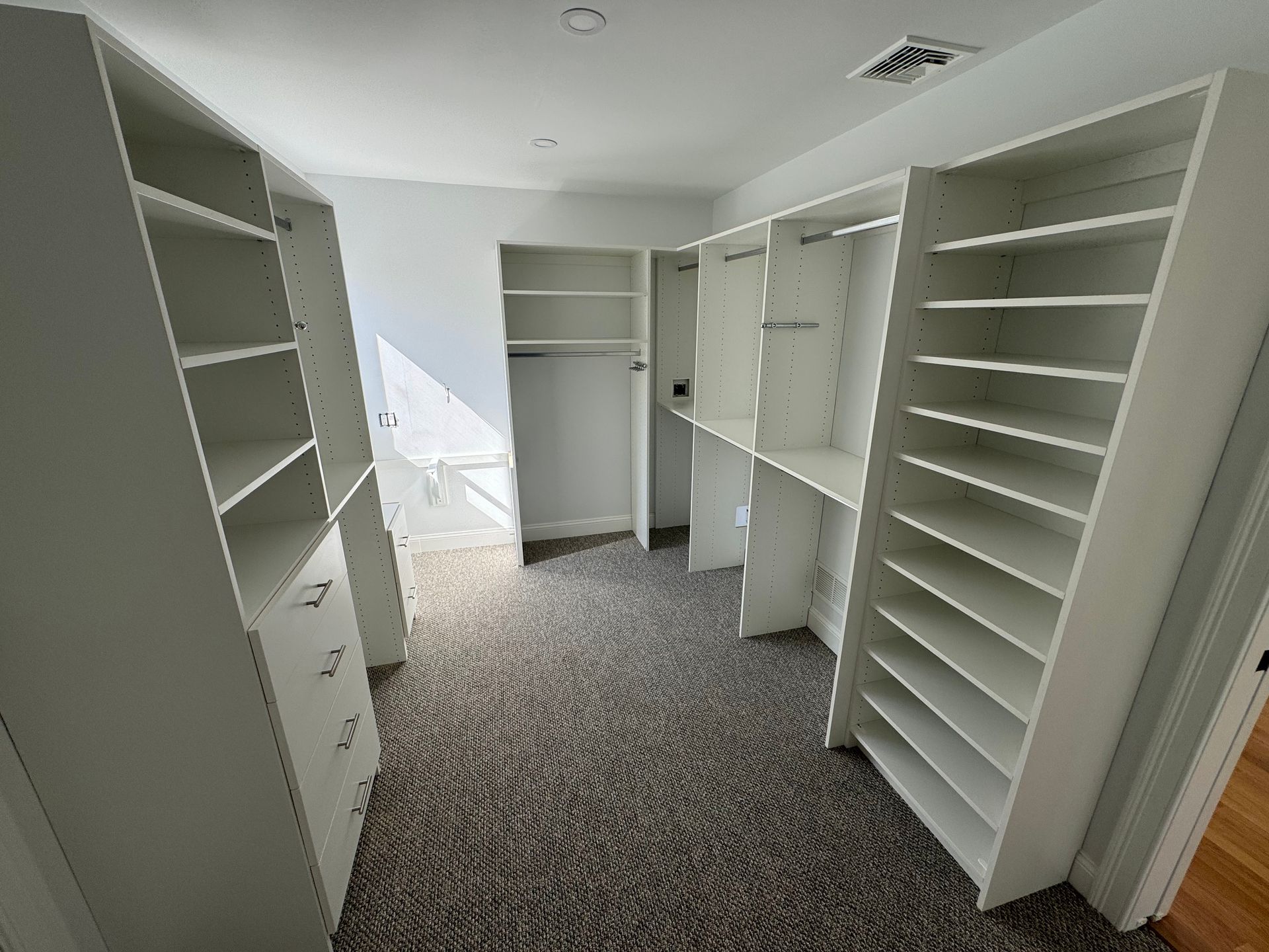 A walk in closet with lots of shelves and drawers.