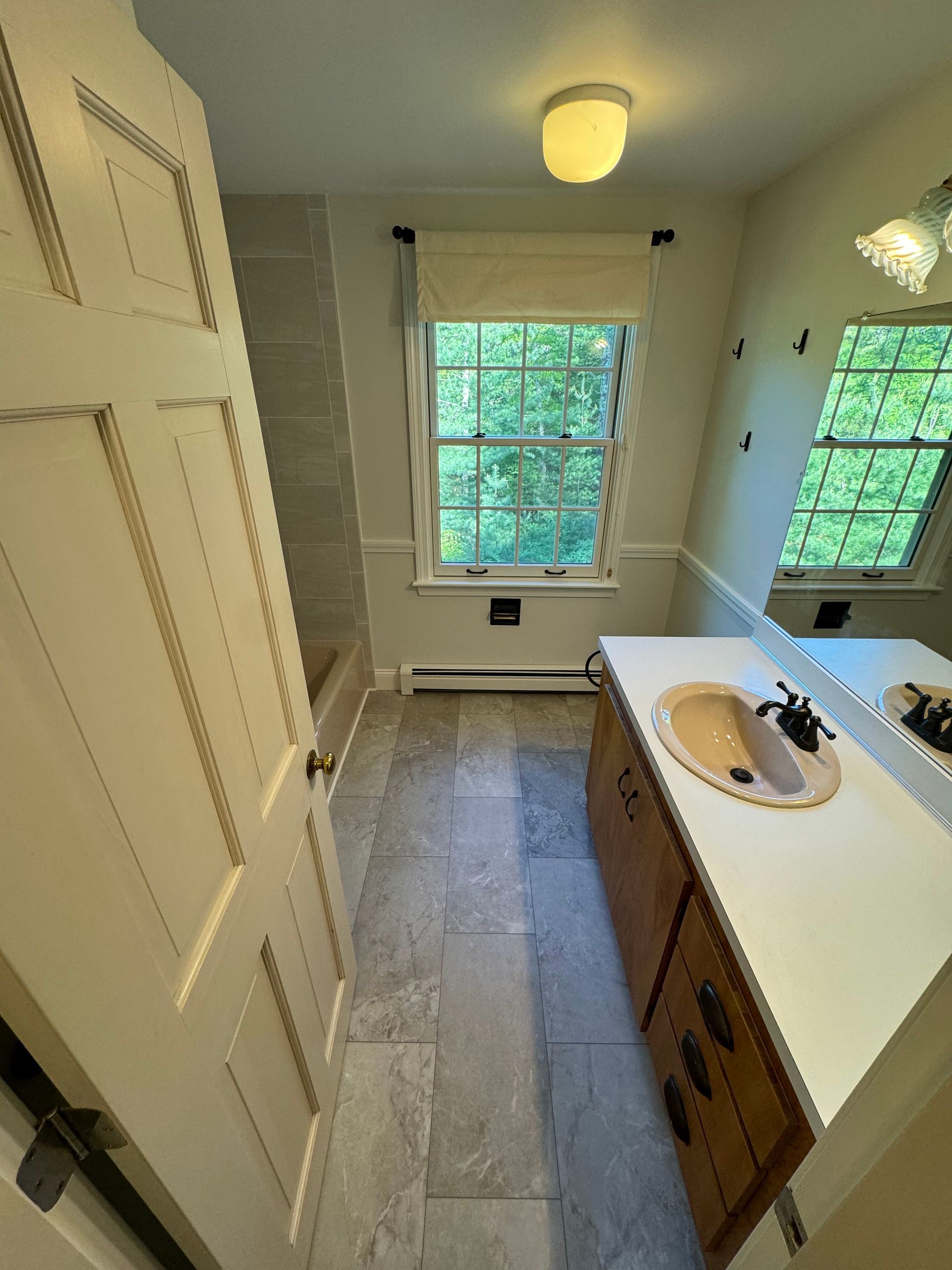 A bathroom with a sink , mirror and window