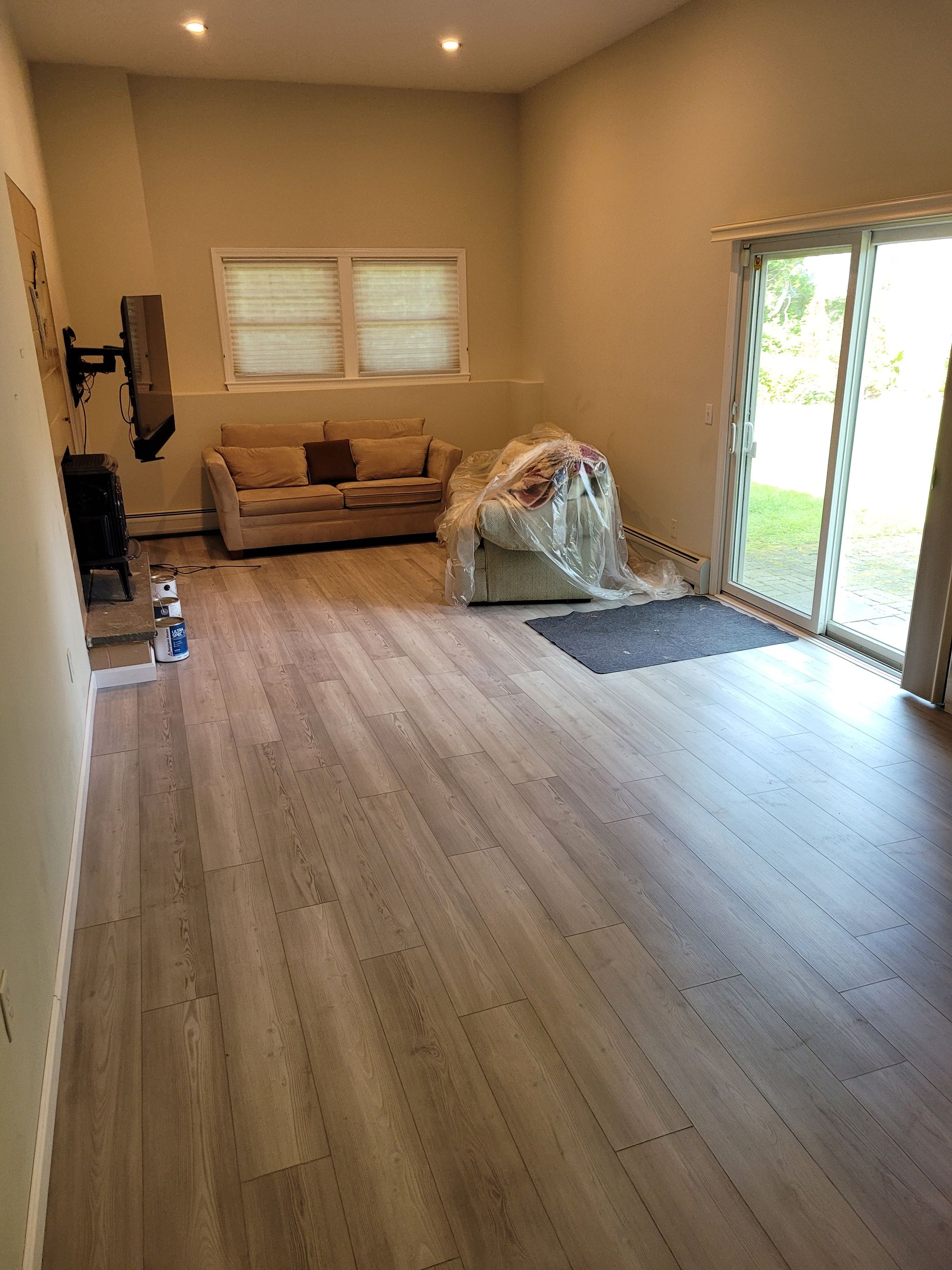 A living room with a couch , television , and sliding glass doors.