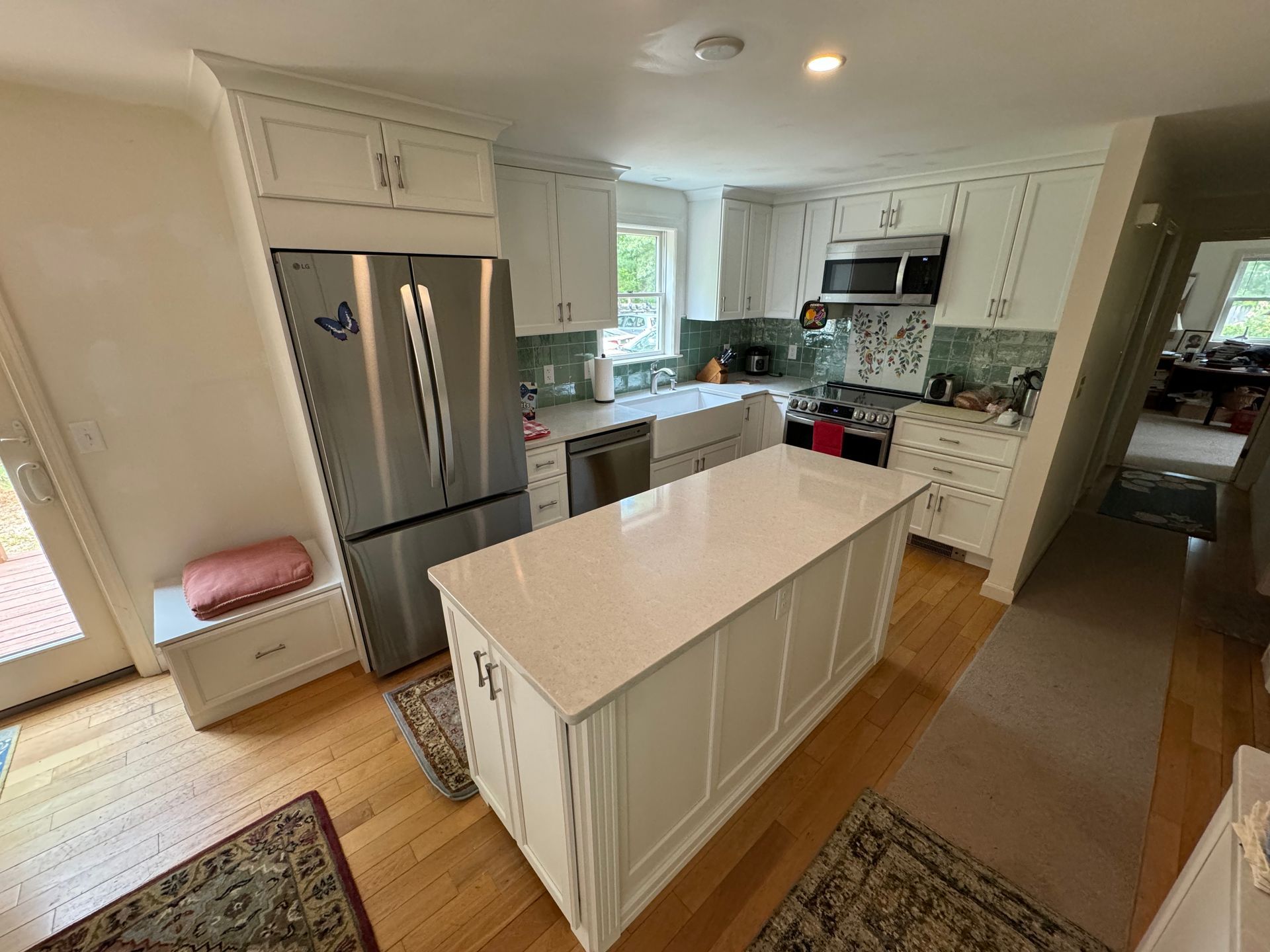A kitchen with white cabinets , stainless steel appliances , and a large island.