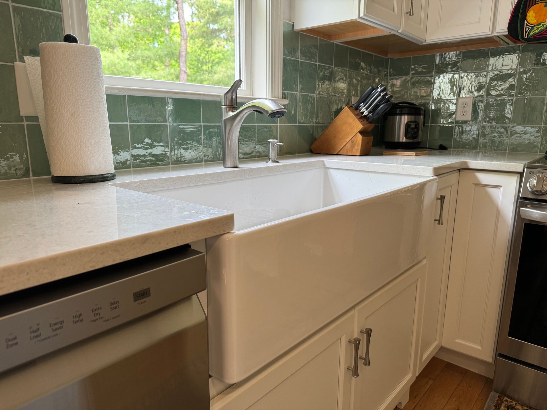 A kitchen with a white sink and a stainless steel dishwasher