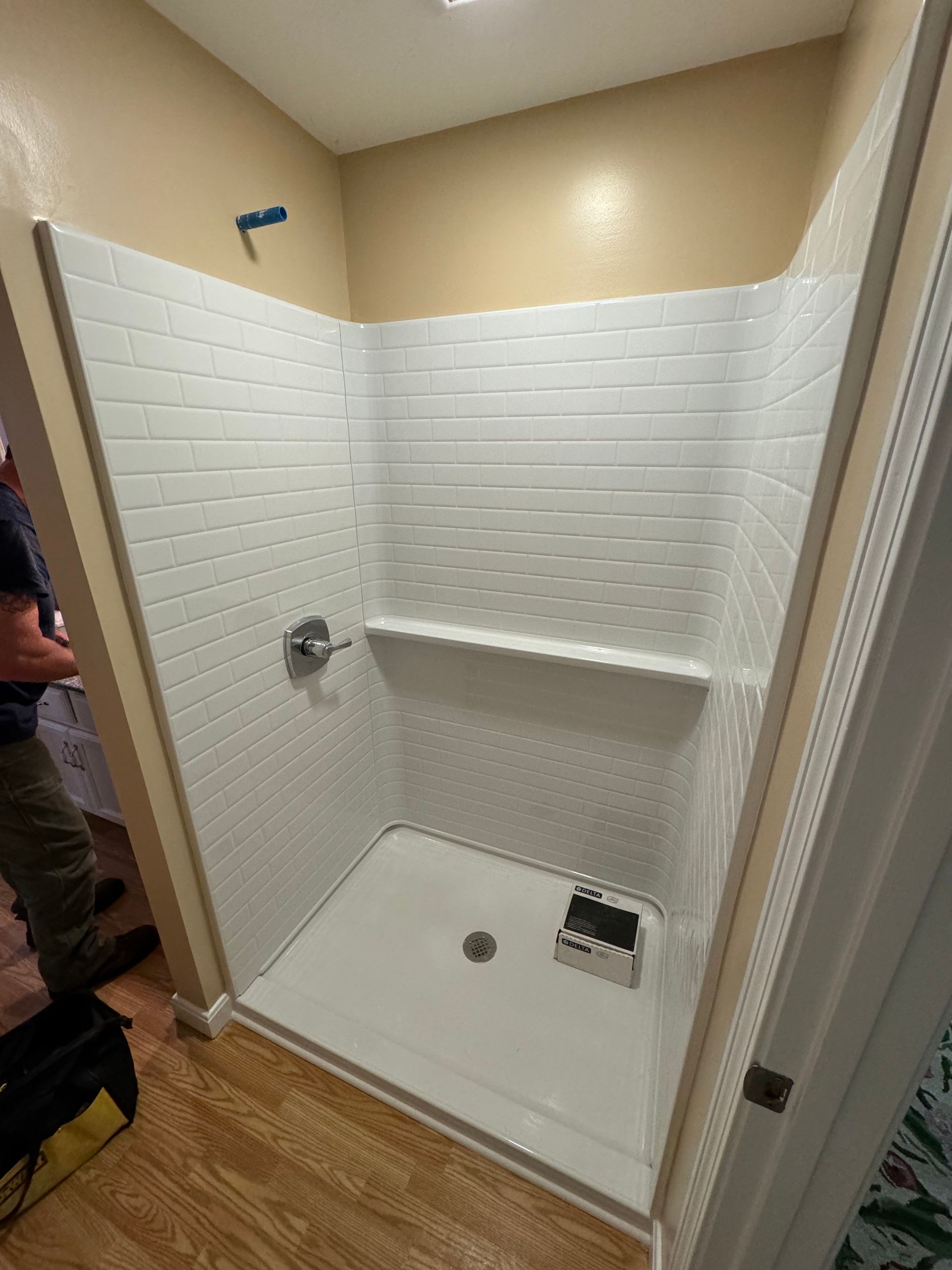 A man is standing in a bathroom next to a shower stall.
