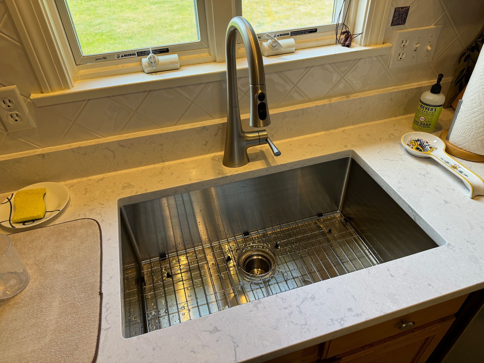 A kitchen sink with a faucet and a window in the background.