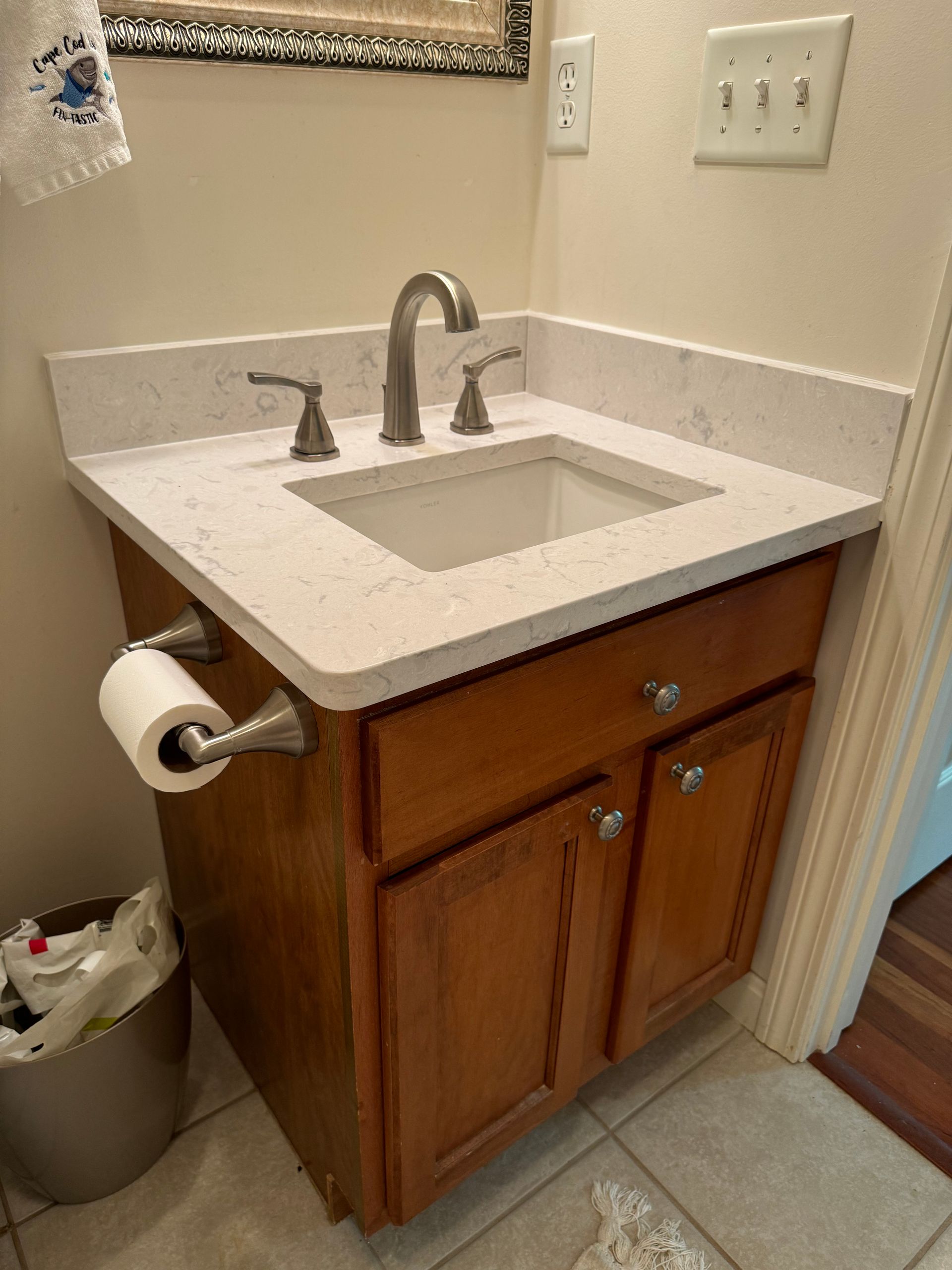 A bathroom vanity with a sink , faucet , and toilet paper holder.
