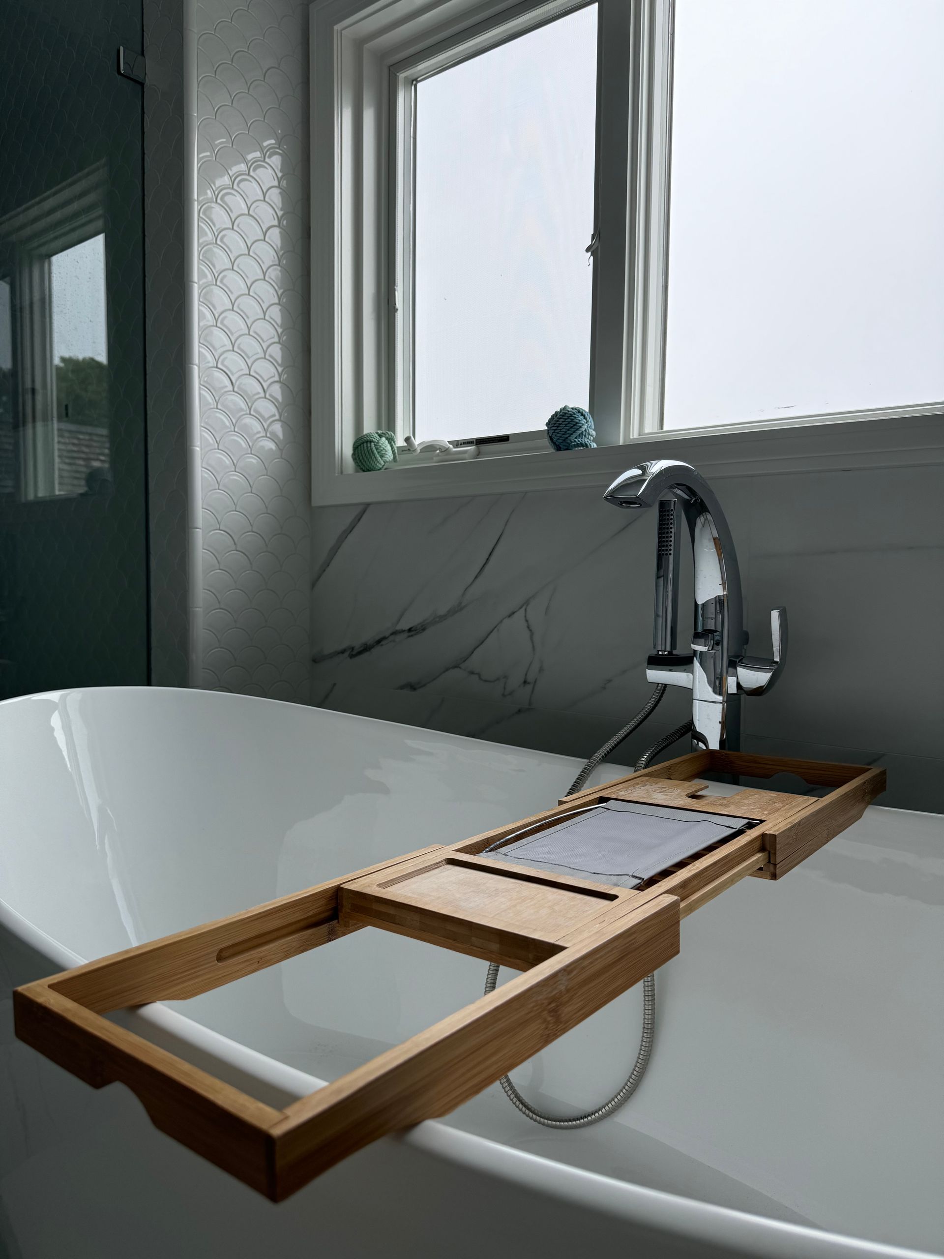 A bathtub with a wooden bathtub tray on top of it.