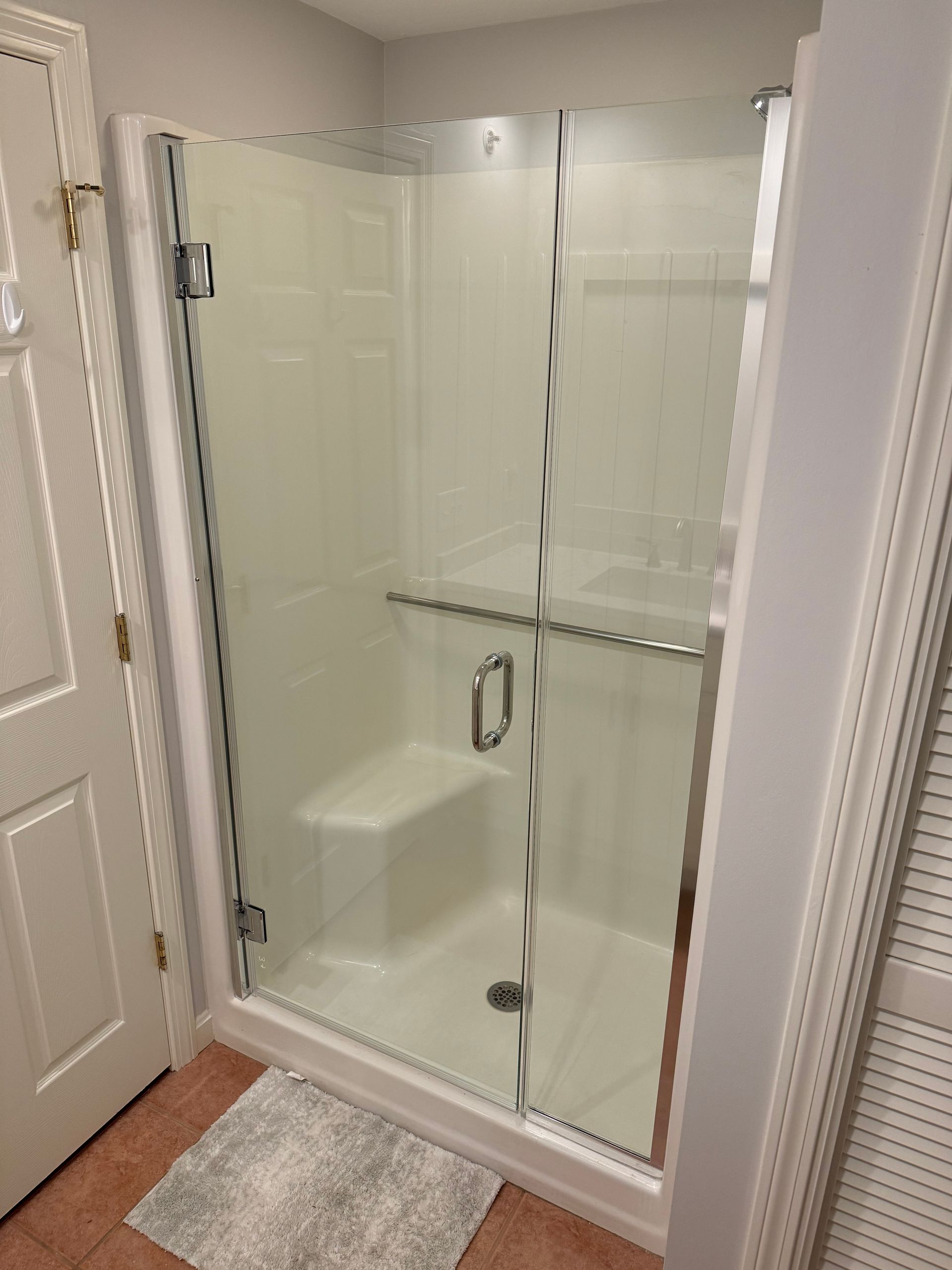 A bathroom with a walk in shower with a glass door.