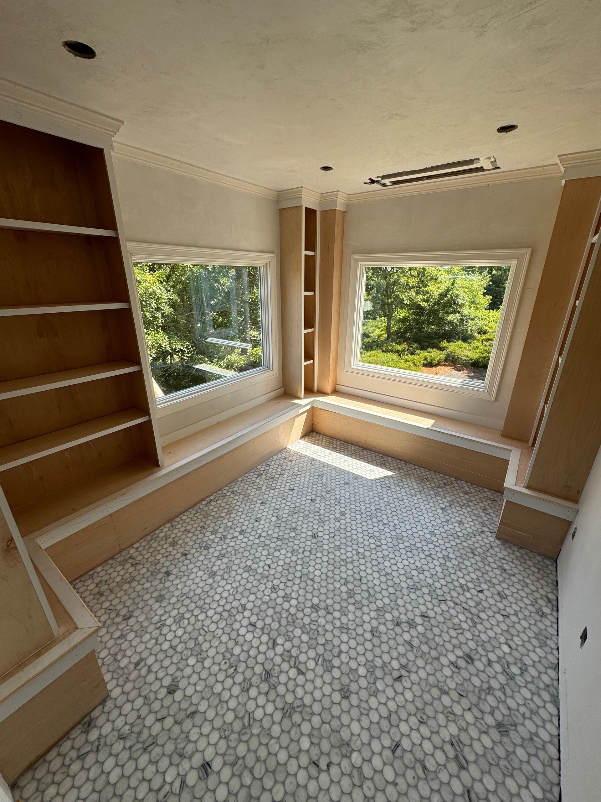 A room with a window , shelves , and a tiled floor.