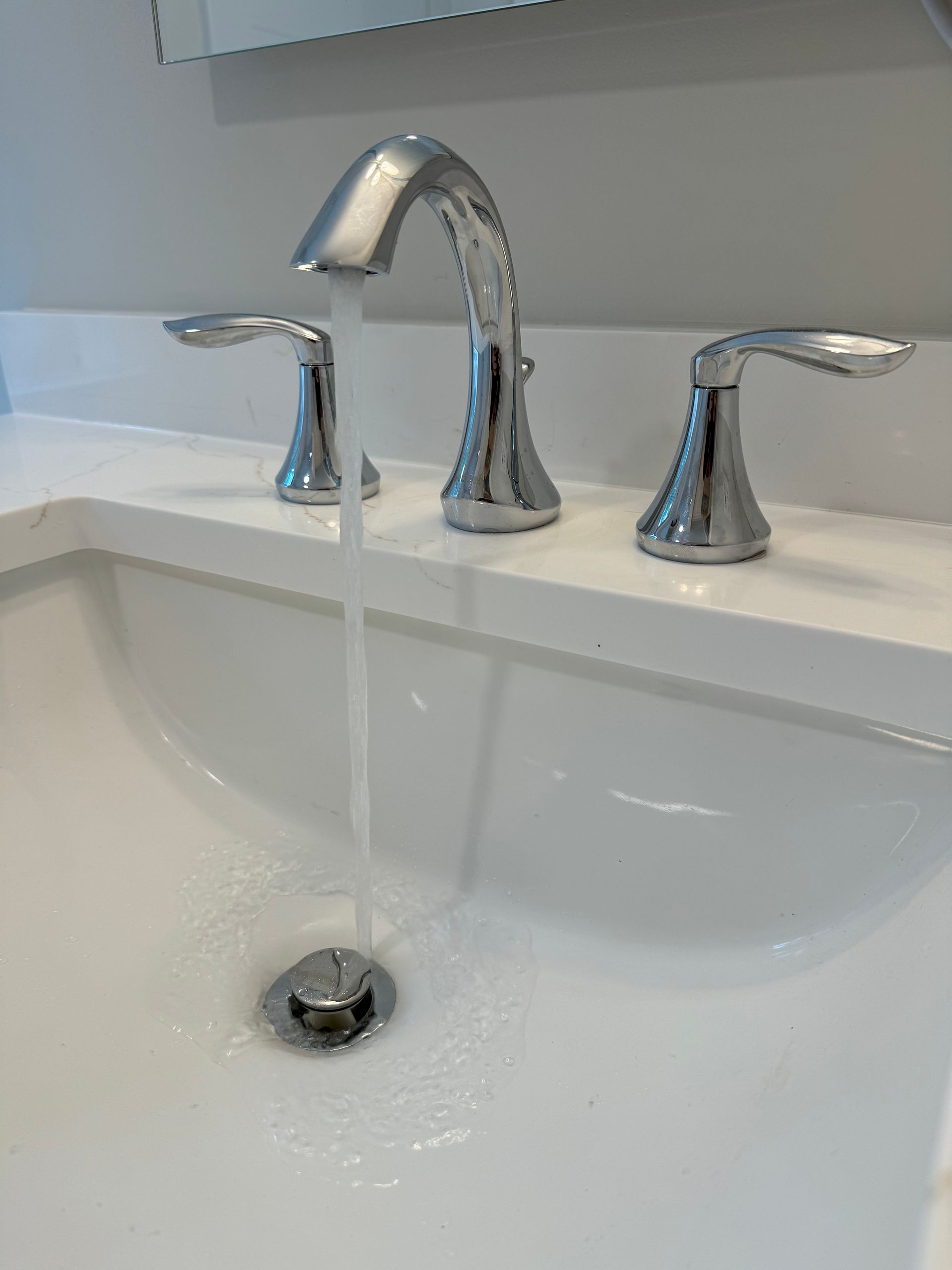 A bathroom sink with water running from the faucet