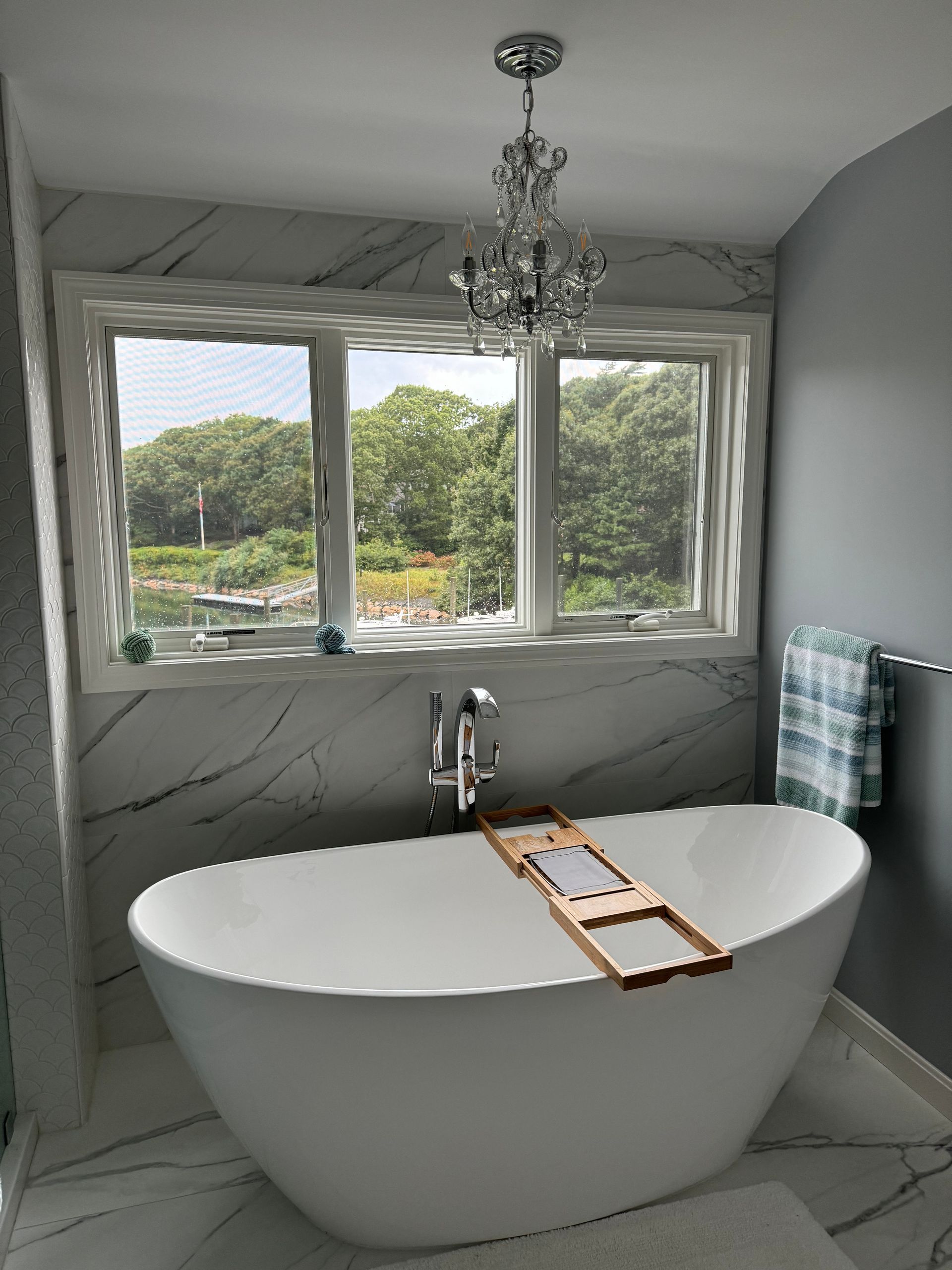 A bathtub in a bathroom with a window and a chandelier.