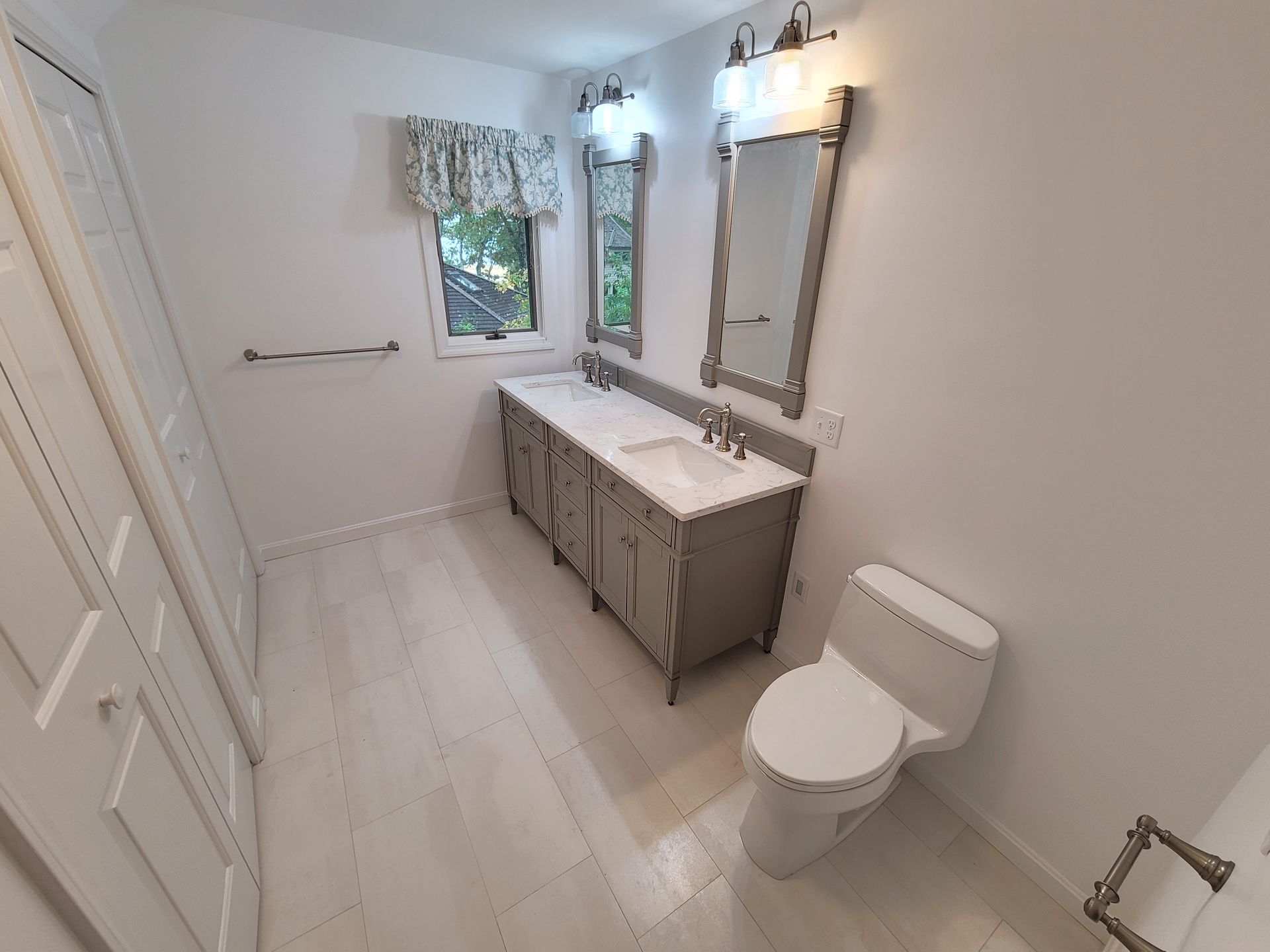 A bathroom with two sinks , a toilet , and two mirrors.