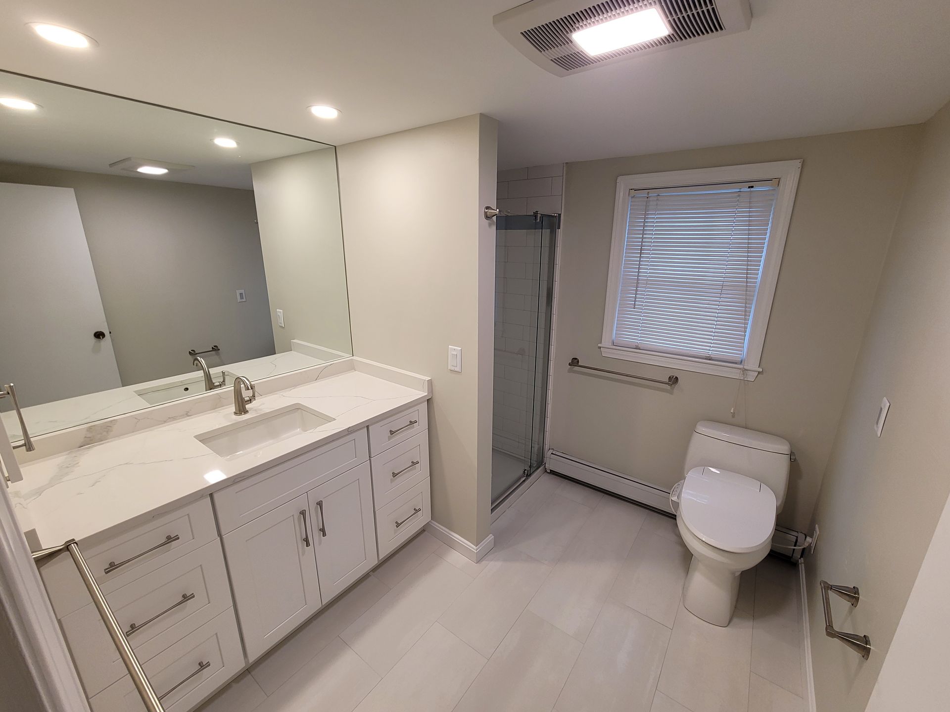 A bathroom with a toilet , sink and mirror.