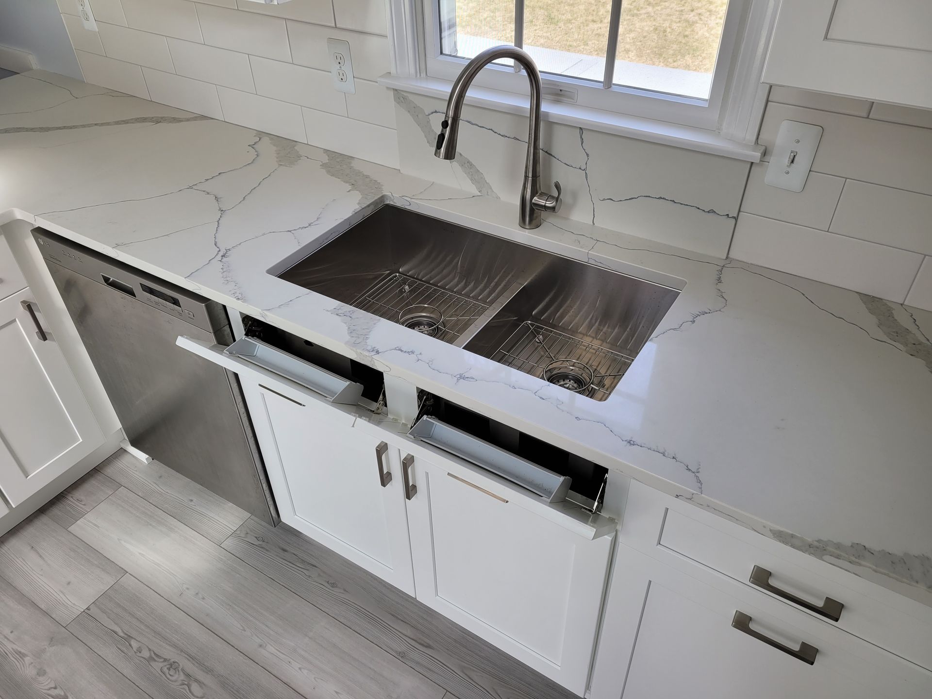A kitchen with white cabinets and a stainless steel sink.