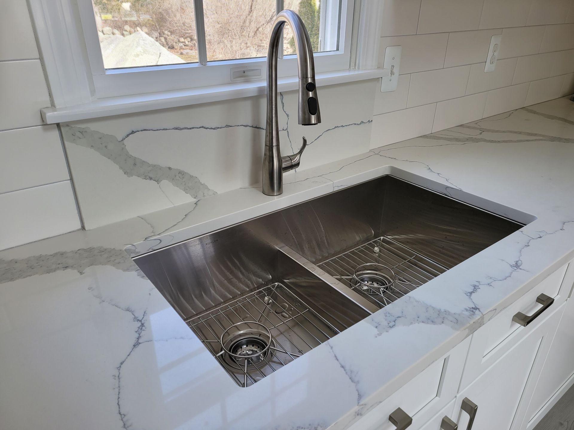 A kitchen sink with a faucet and a window