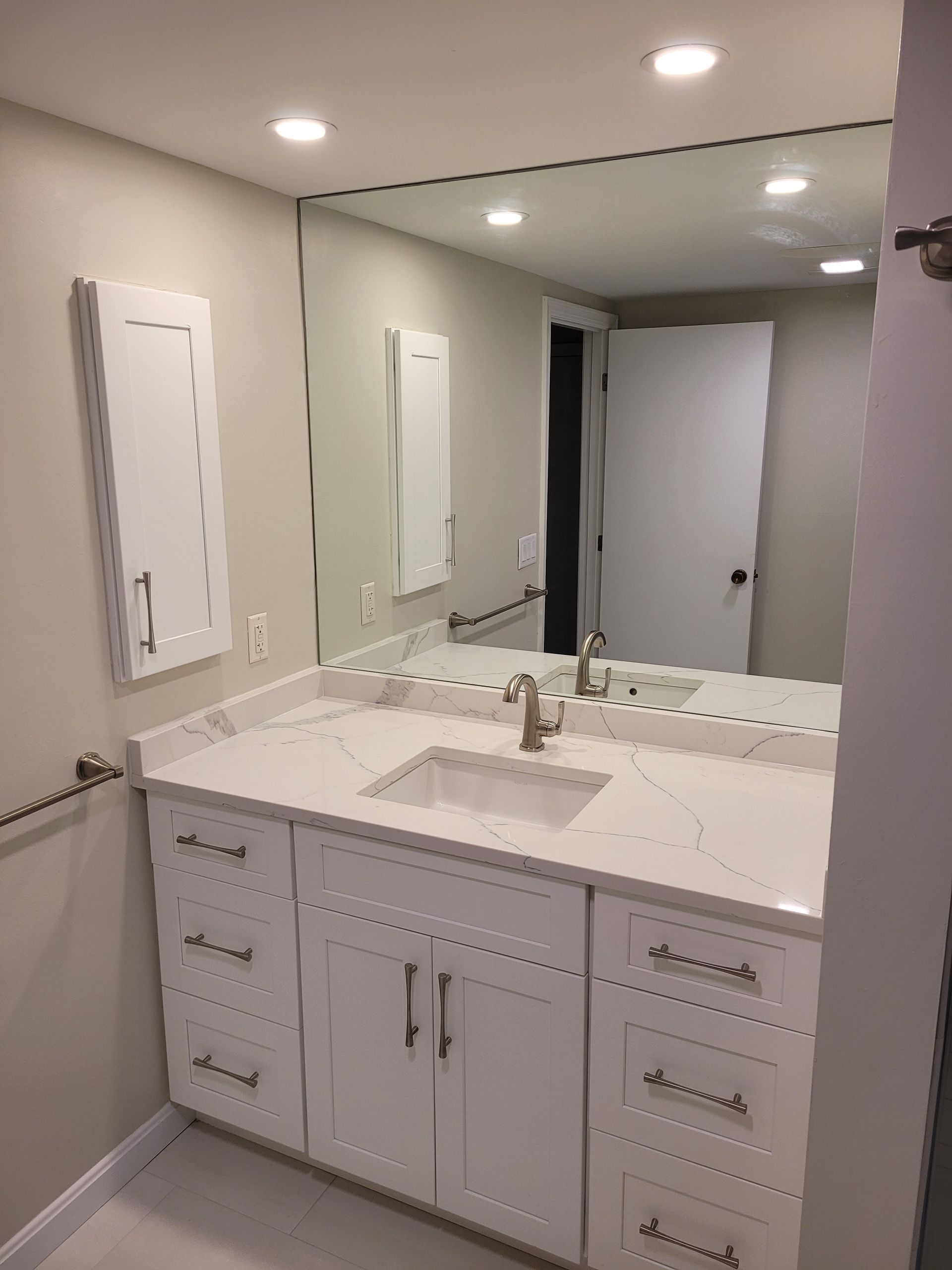 A bathroom with a sink , mirror and cabinets.