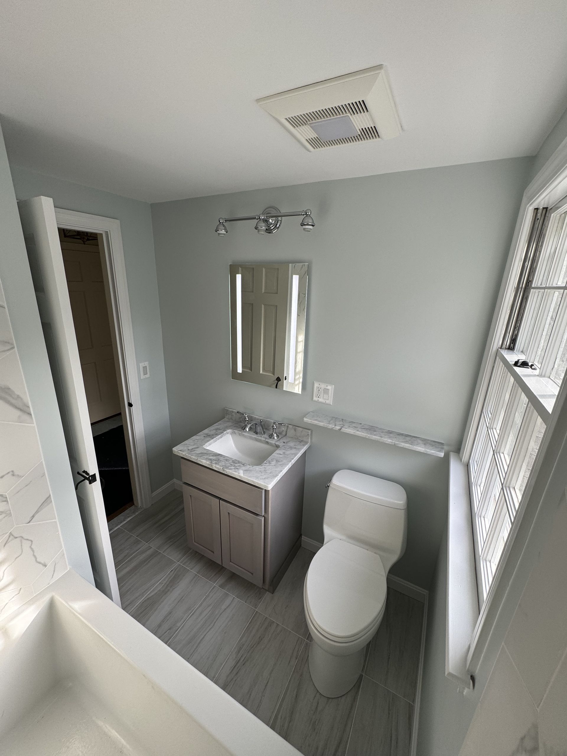 A bathroom with a toilet , sink and mirror.