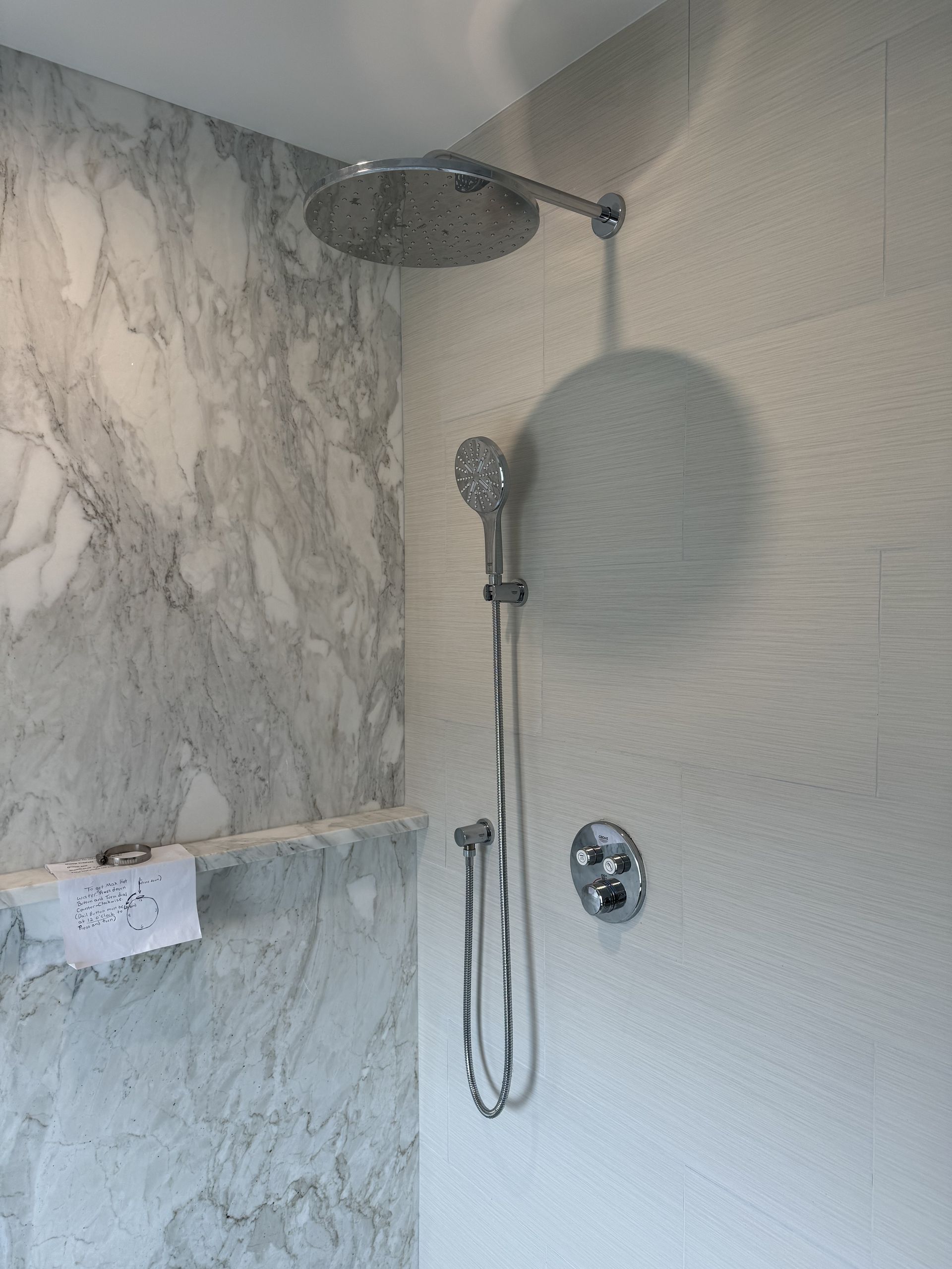 A shower head is hanging from the ceiling in a bathroom.