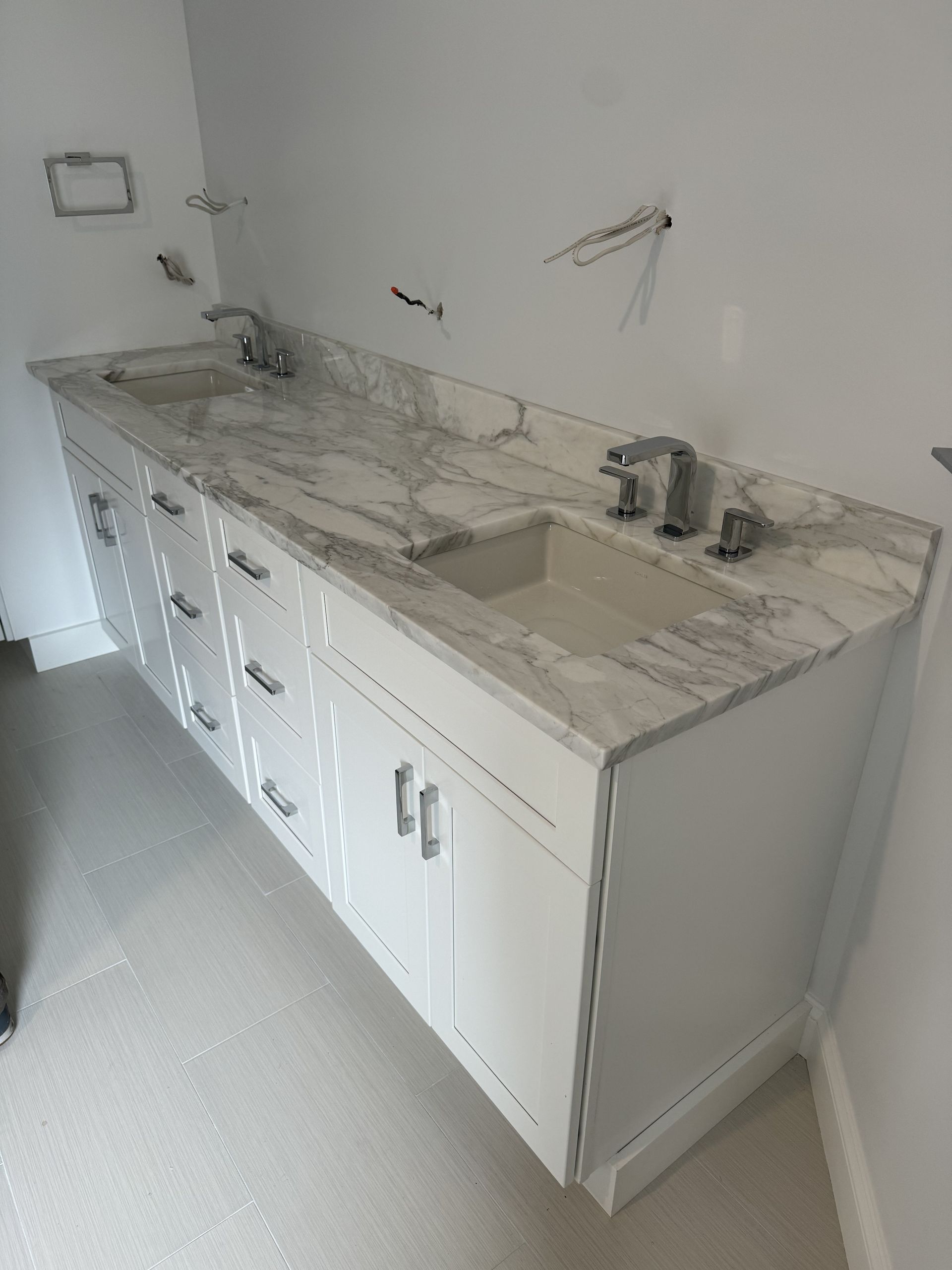 A bathroom with two sinks and white cabinets