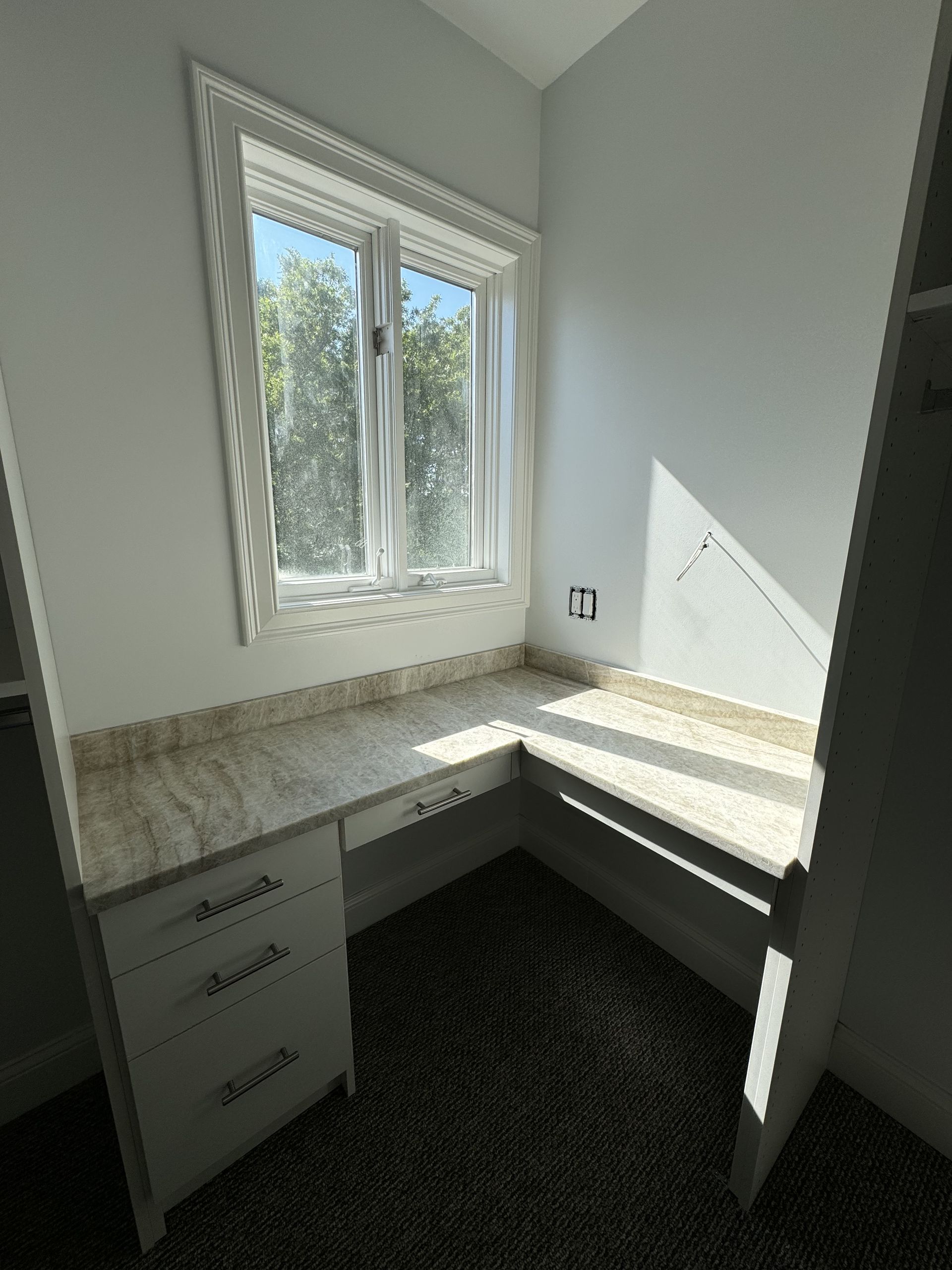 A corner of a room with a window and a desk.