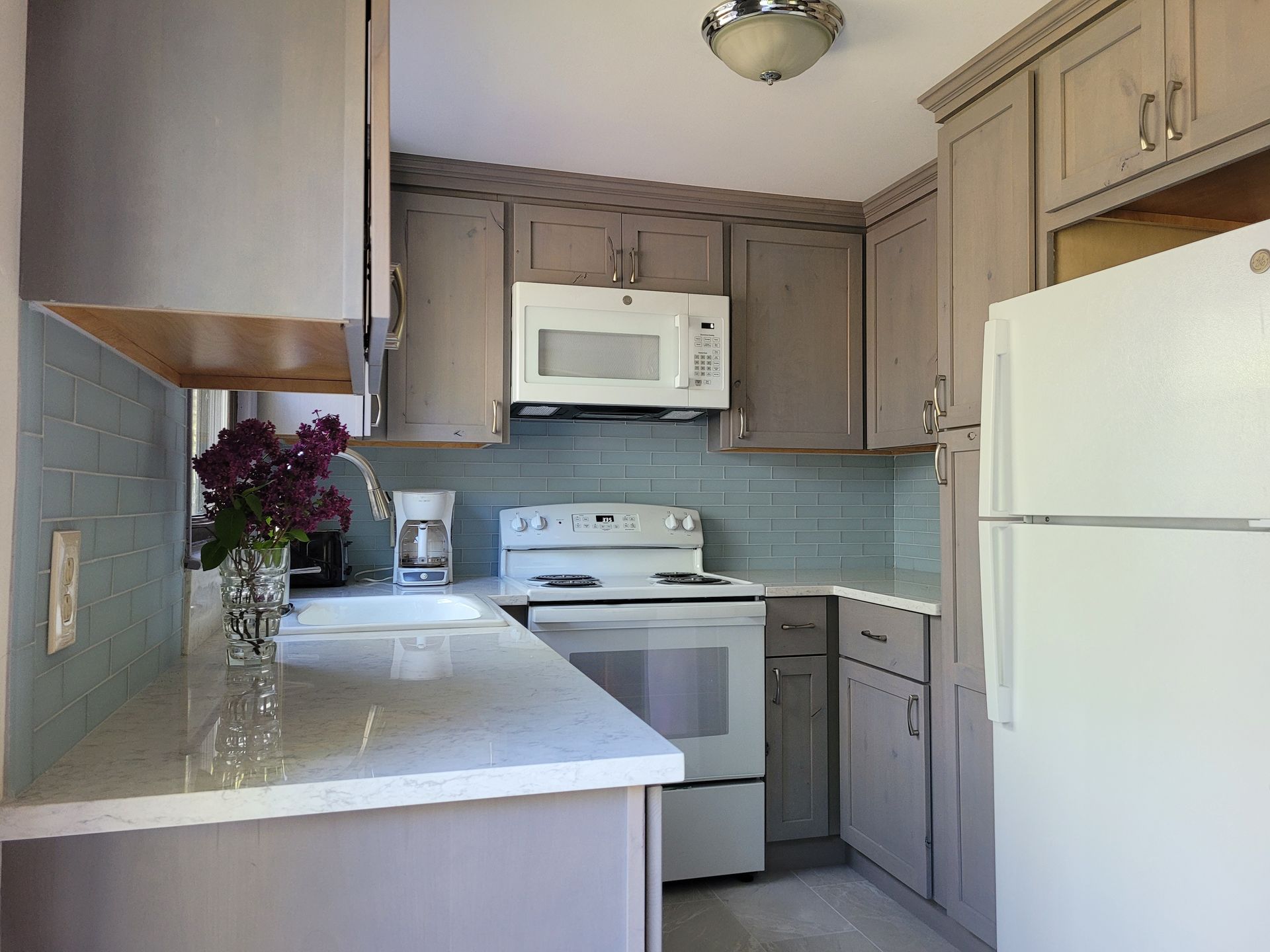 A kitchen with a stove , refrigerator , microwave and sink