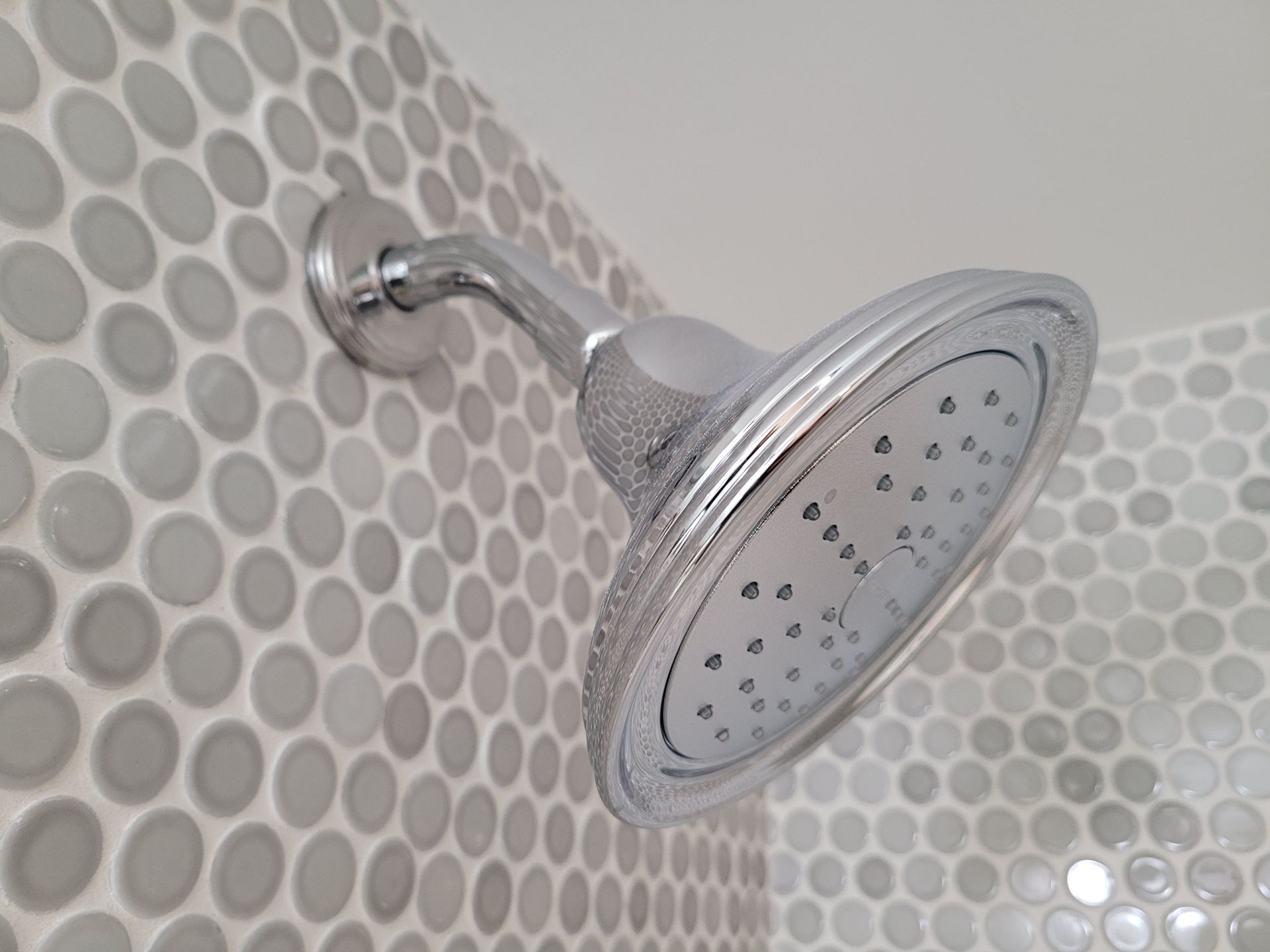 A shower head is hanging on a tiled wall.
